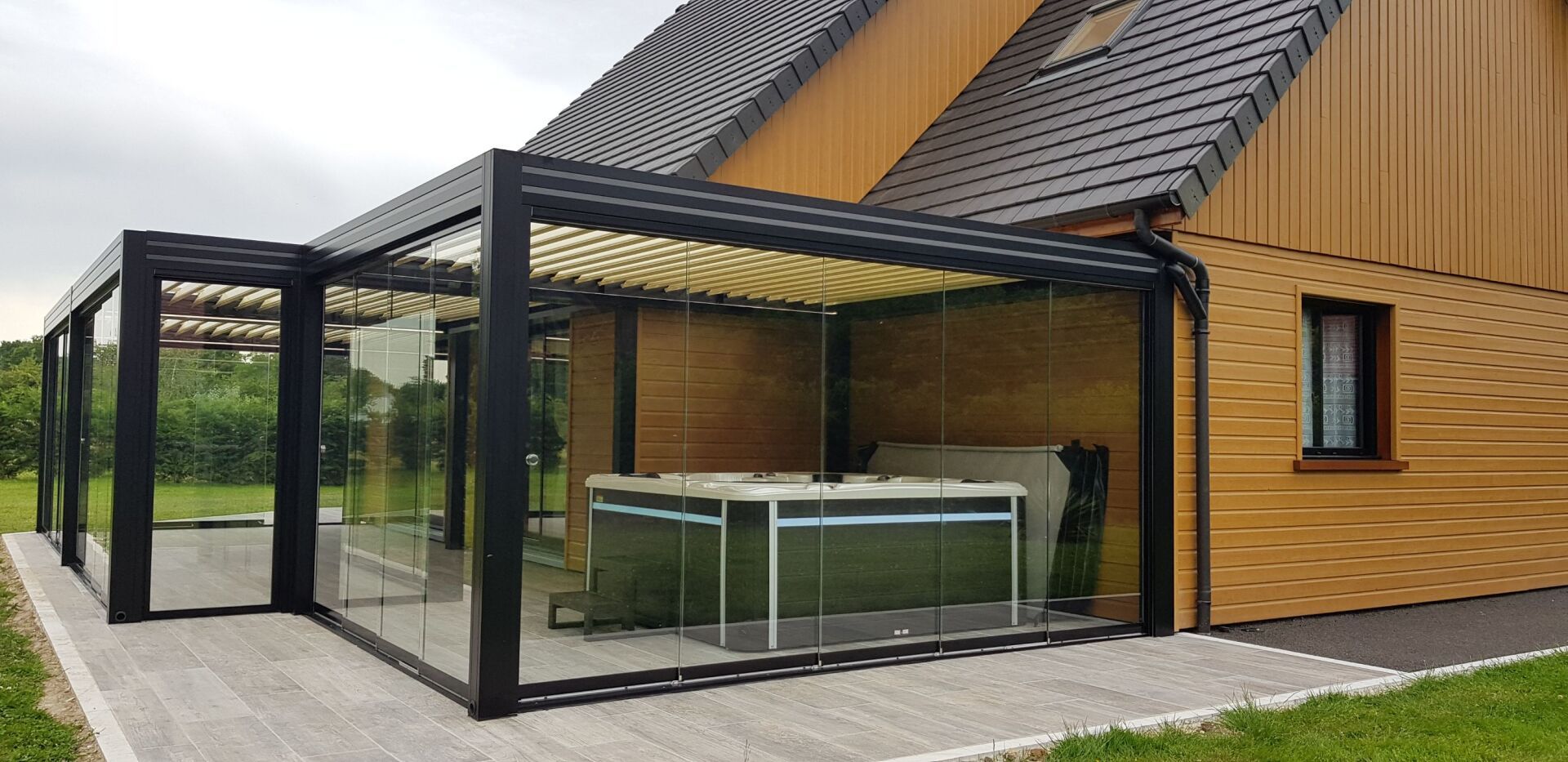 Une maison avec une pergola et un jacuzzi devant.