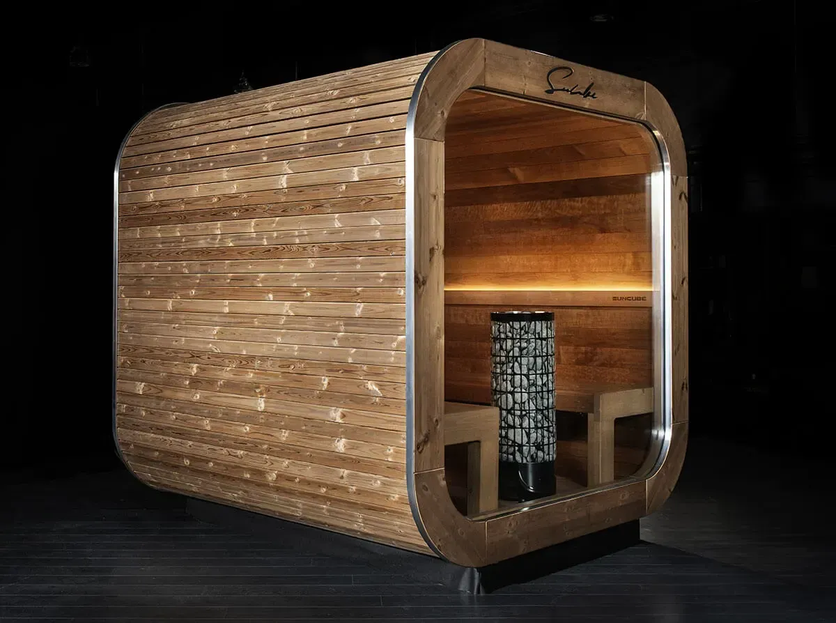 Un sauna en bois est posé sur un plancher en bois dans une pièce sombre.