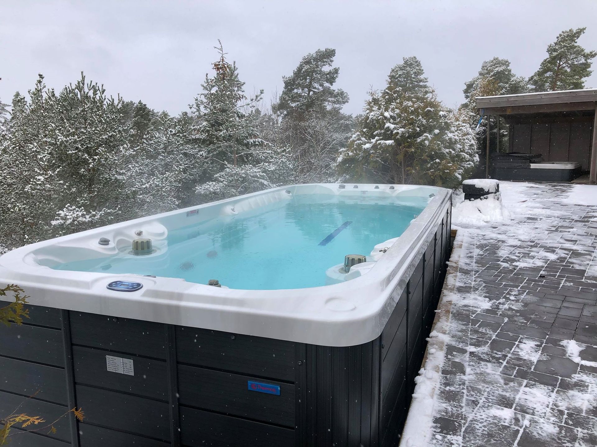 Une grande piscine est posée sur un patio couvert de neige.