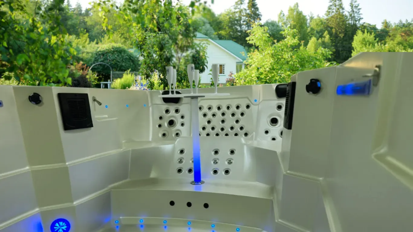 Un jacuzzi blanc avec une lumière bleue qui en sort et une maison en arrière-plan.