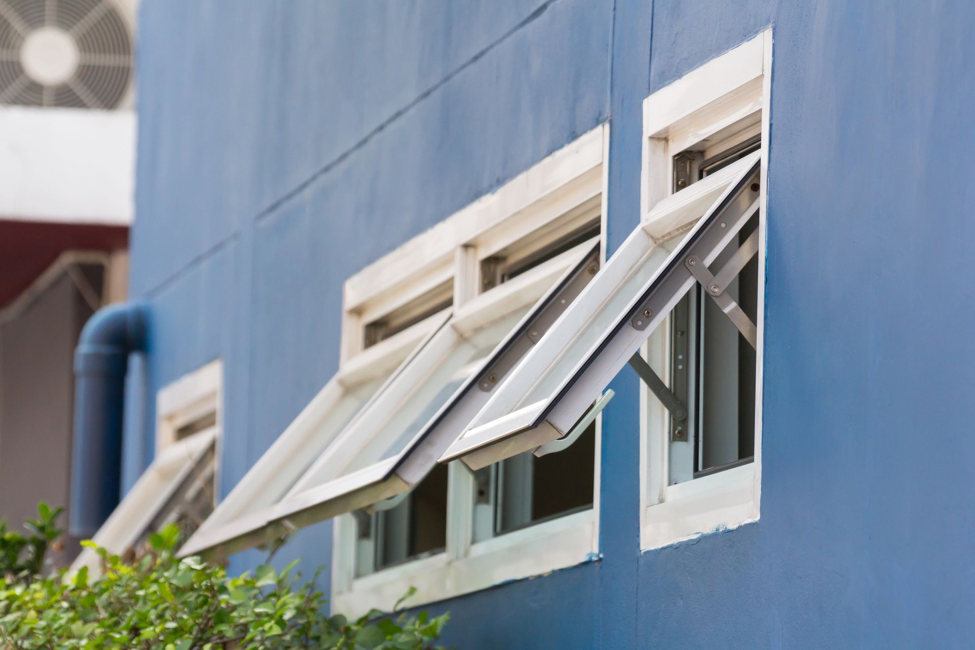 Blue Building With White Windows Partly Open, With Greenery Below — Working Windows in Caloundra, QLD