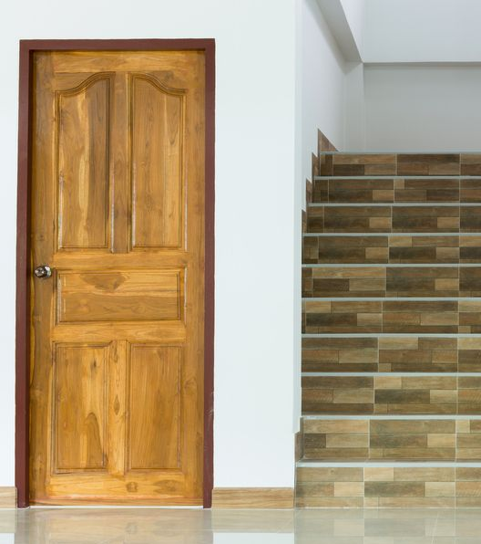 Wooden Door Beside a Tiled Staircase in A White Interior Hallway — Working Windows in Northern Rivers, NSW