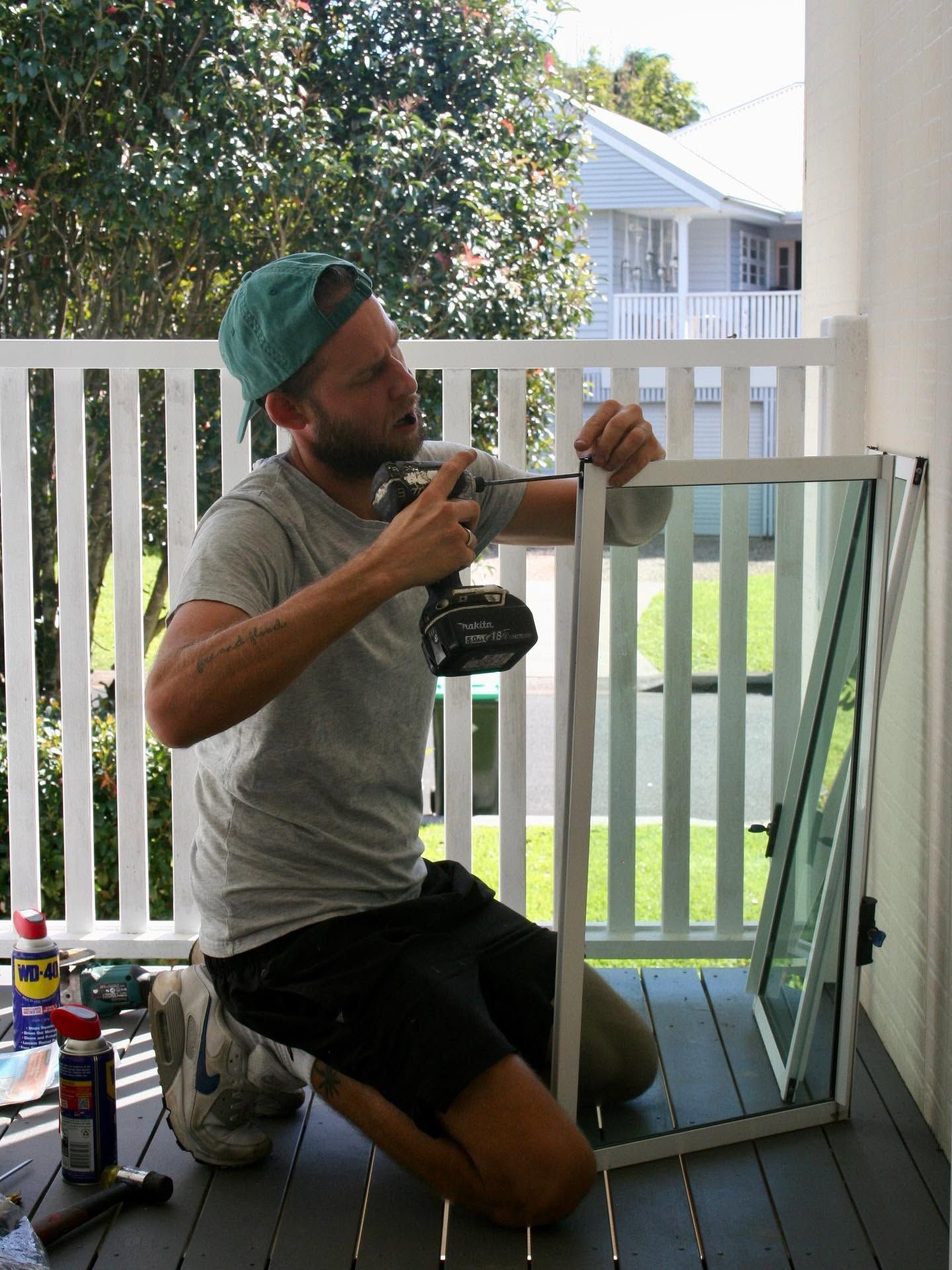 Man Kneeling on a Porch, Measuring a White Window Frame Beside an Open Window — Working Windows in Caloundra, QLD
