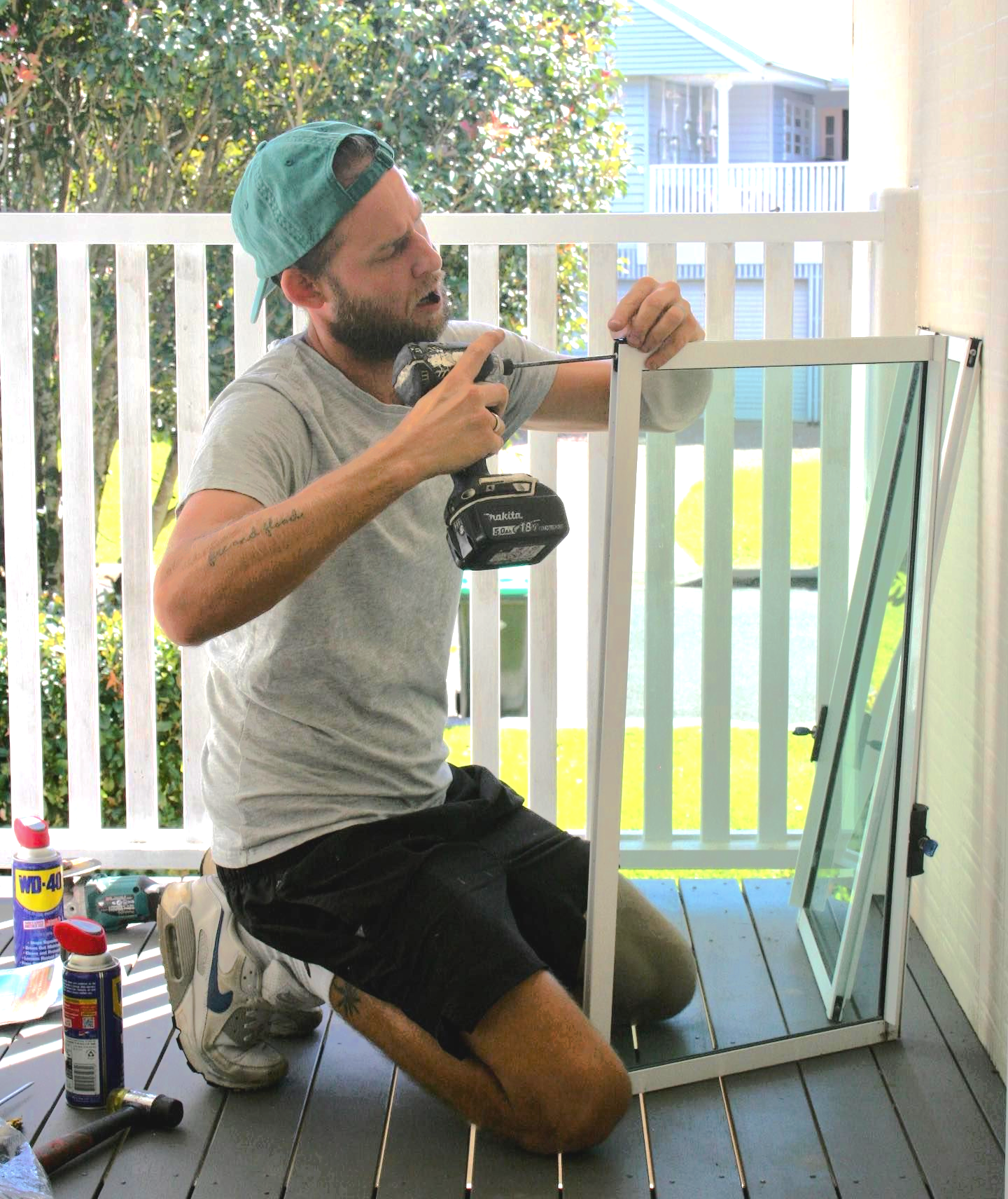 Person in a Baseball Cap Cutting Screen Mesh on a Sliding Door Frame Outdoors — Working Windows in Byron Bay, NSW