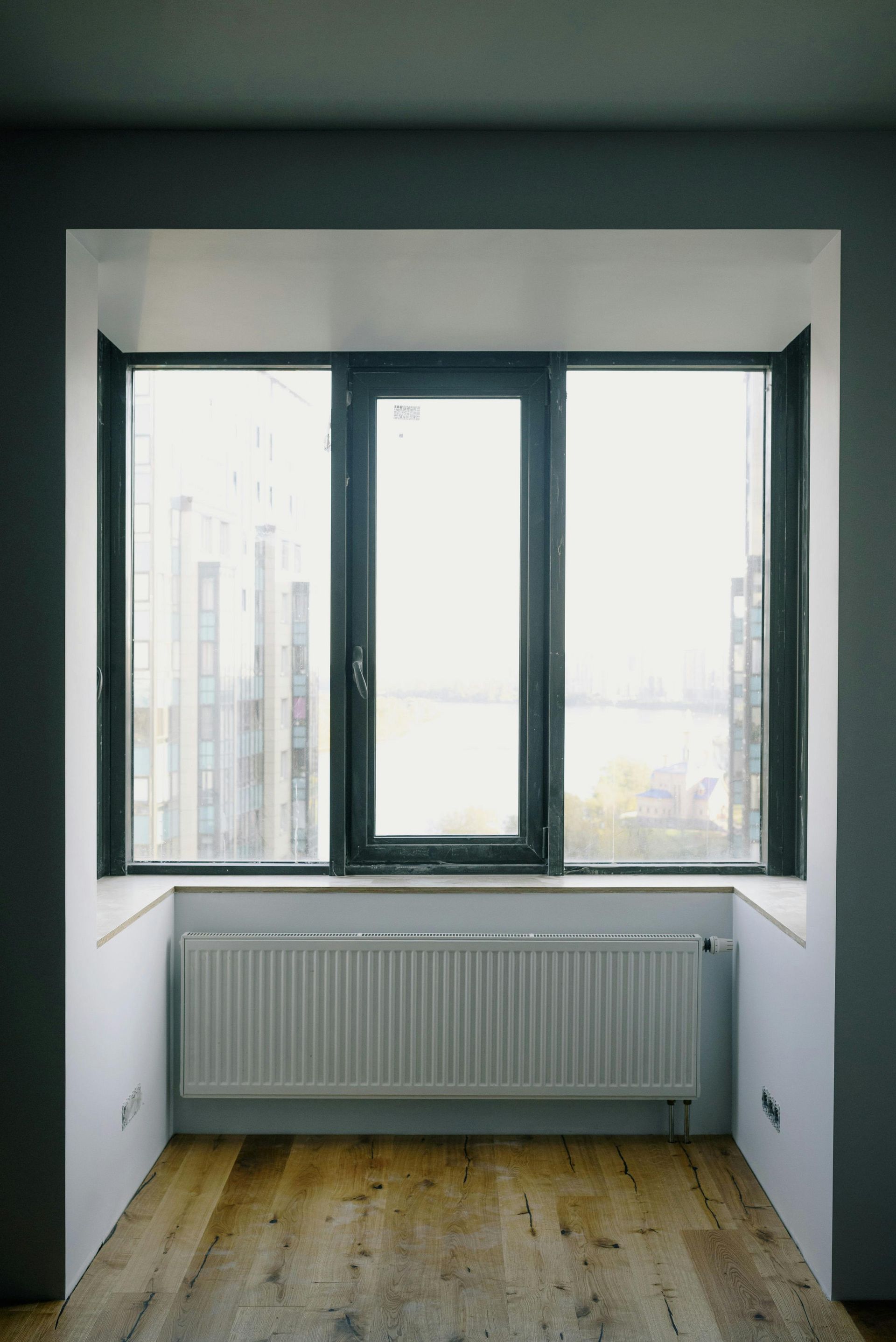 Empty Room With a Large Window, White Radiator, and Wood Floor — Working Windows in Maroochydore, QLD