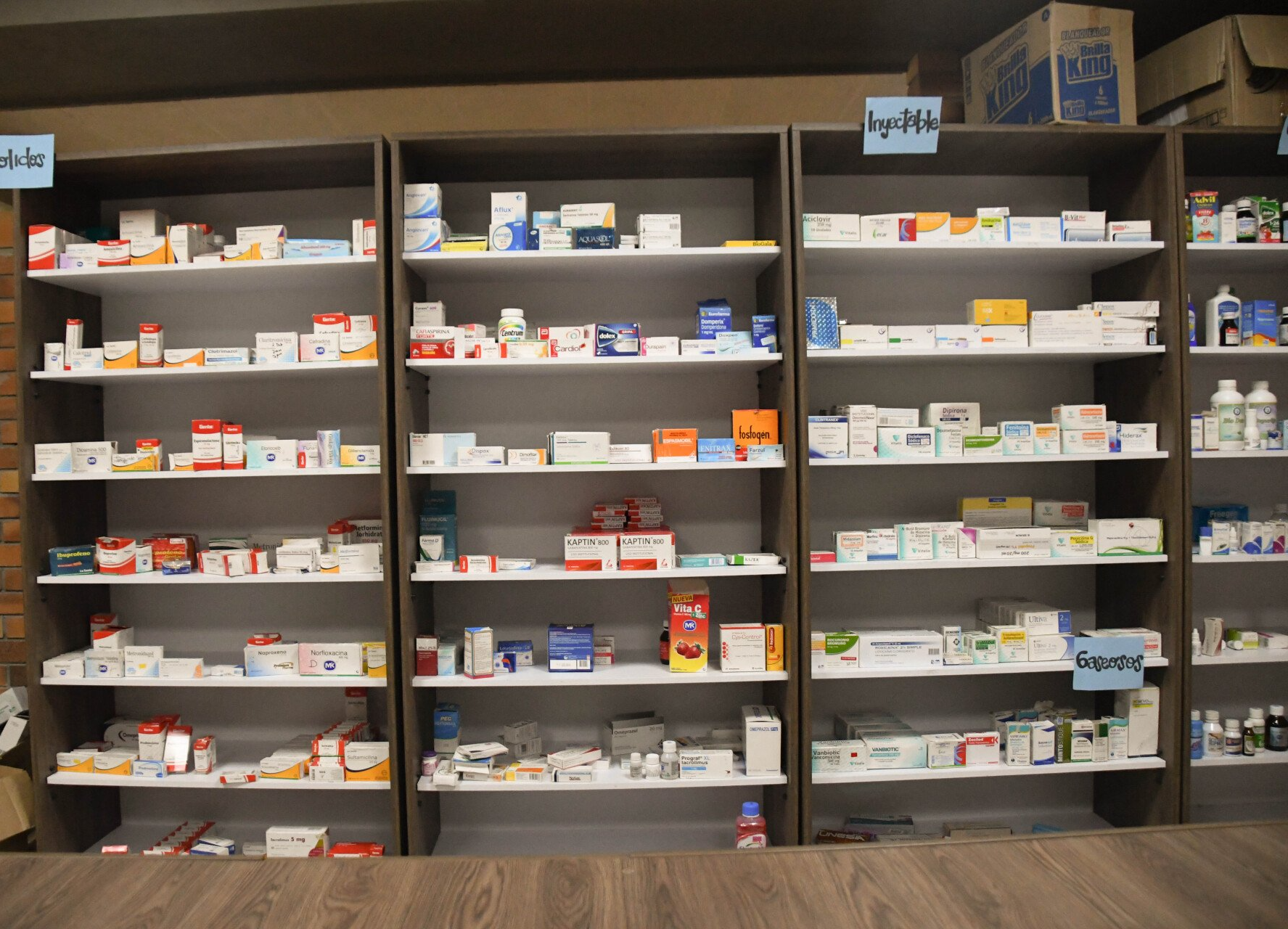 Una fila de estantes llenos de muchos medicamentos en una farmacia.