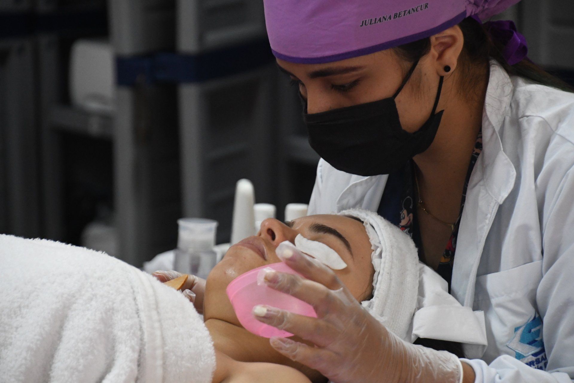 Una mujer que lleva una máscara y guantes está limpiando la cara de una mujer.