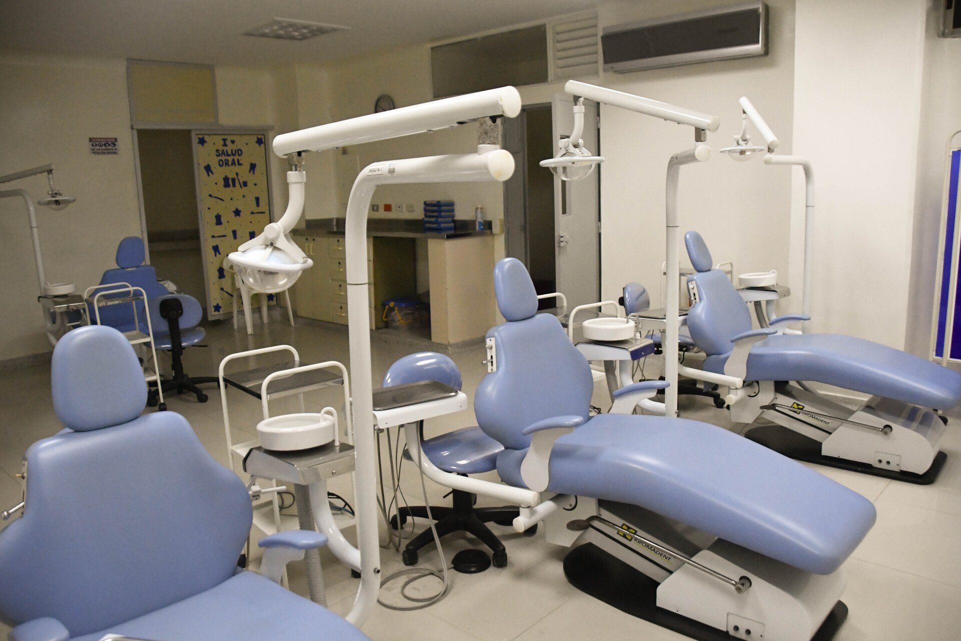 Un consultorio dental con sillas azules y equipo dental.