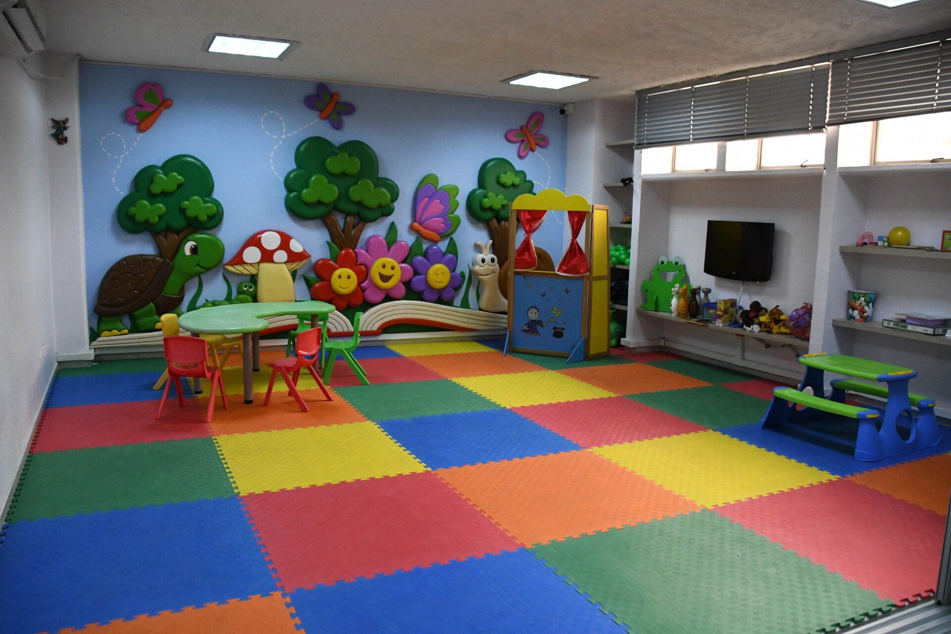Una sala de juegos colorida con mesas y sillas y un cuadro en la pared.