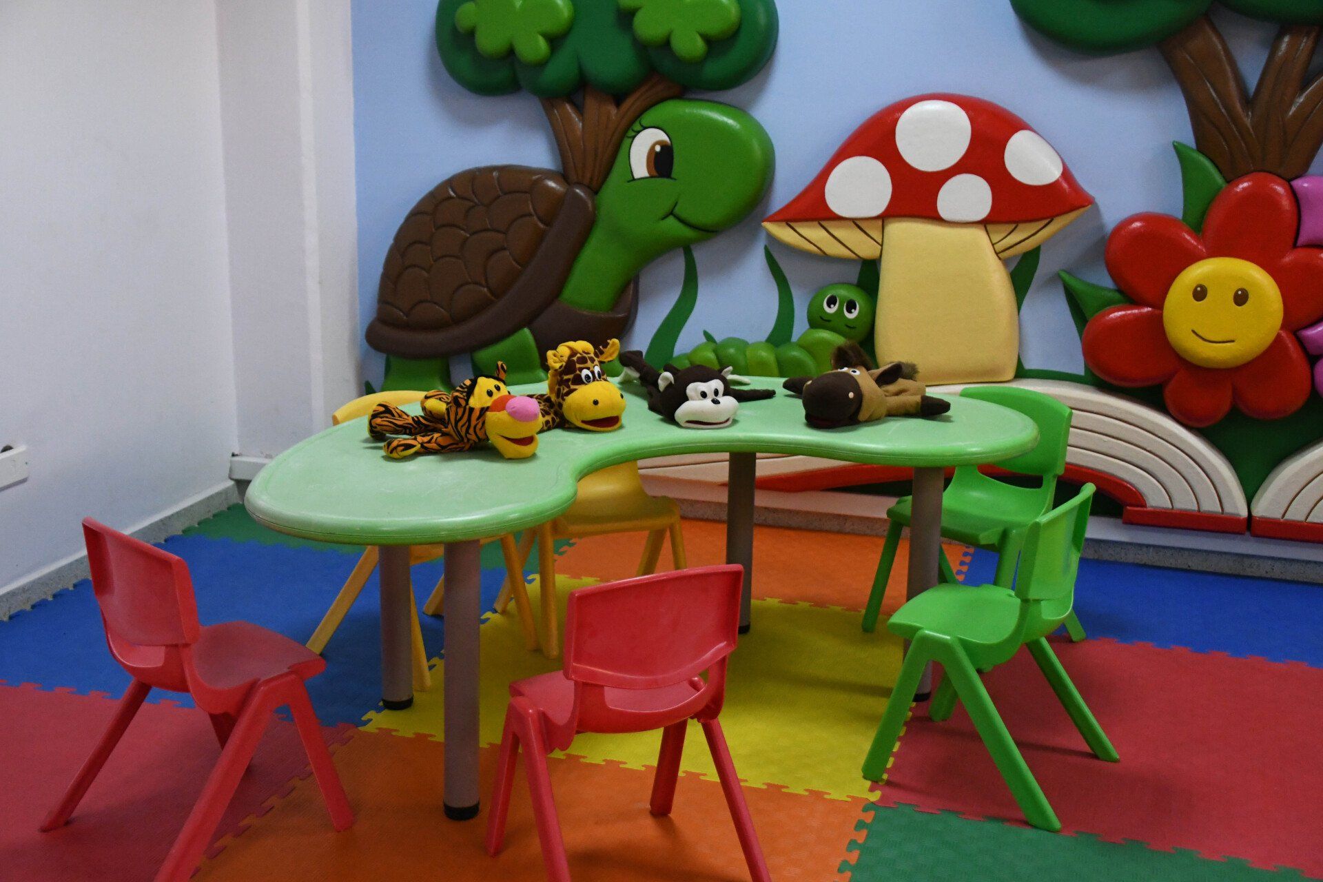 Una habitación con una mesa y sillas con animales de peluche encima.