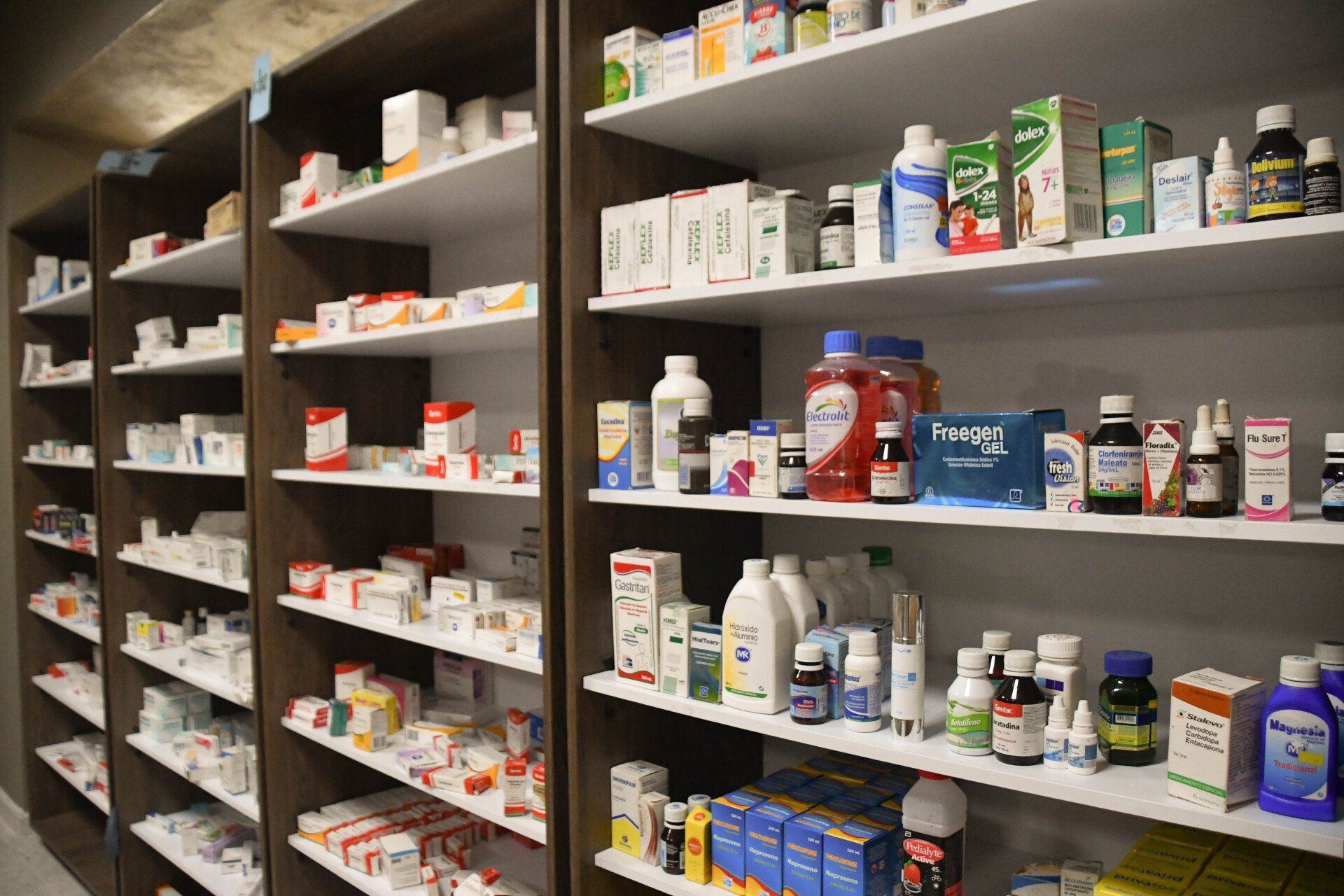 Una fila de estantes llenos de muchos medicamentos en una farmacia.