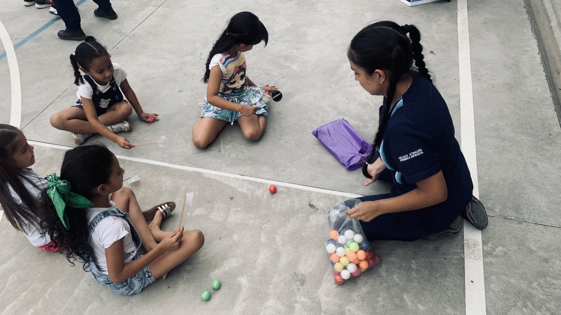 Un grupo de chicas jóvenes están sentadas en el suelo jugando con pelotas.