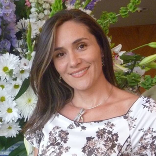 Una mujer sonríe delante de un ramo de flores.