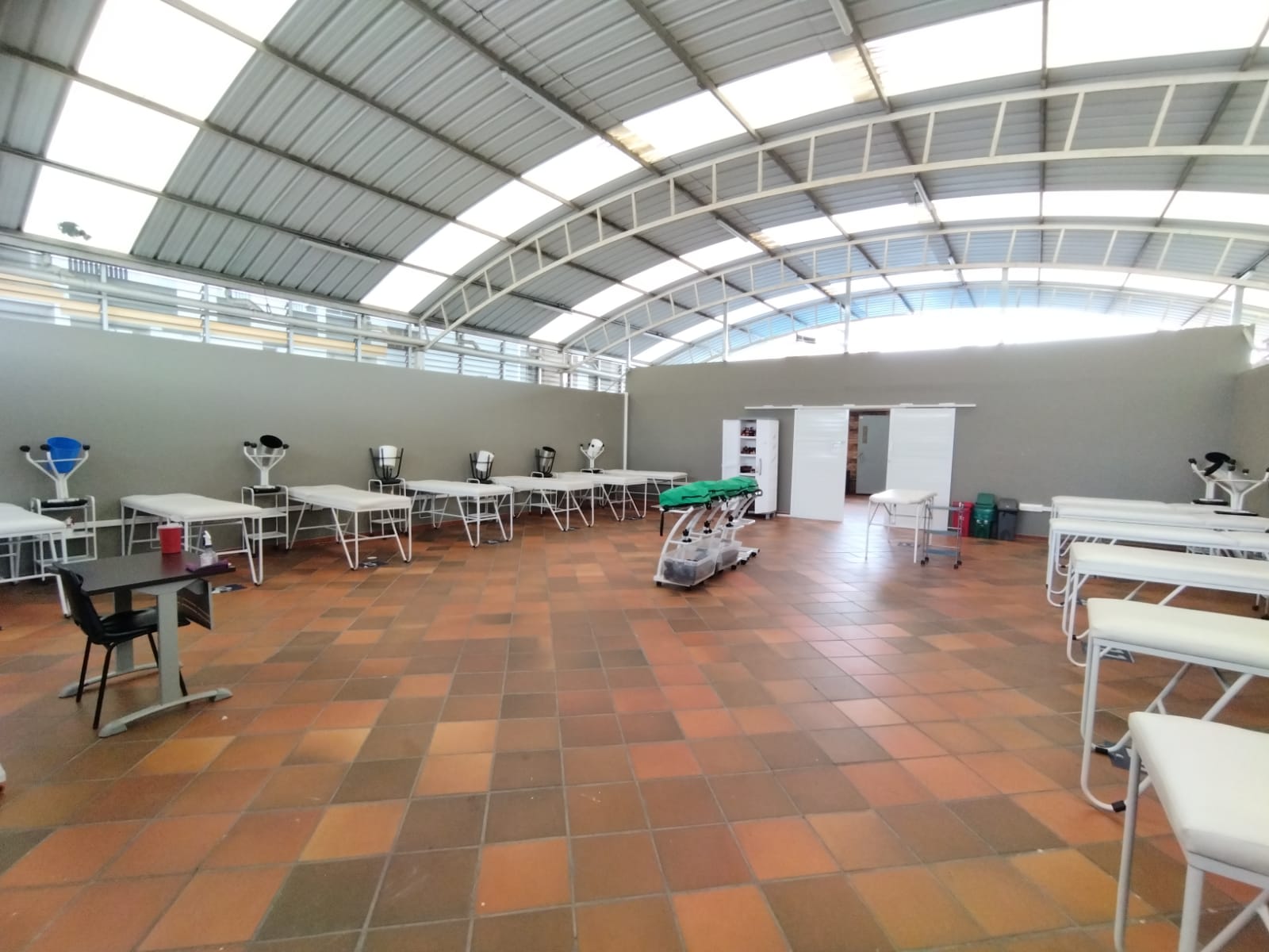 Una gran sala llena de mesas y sillas bajo un techo.