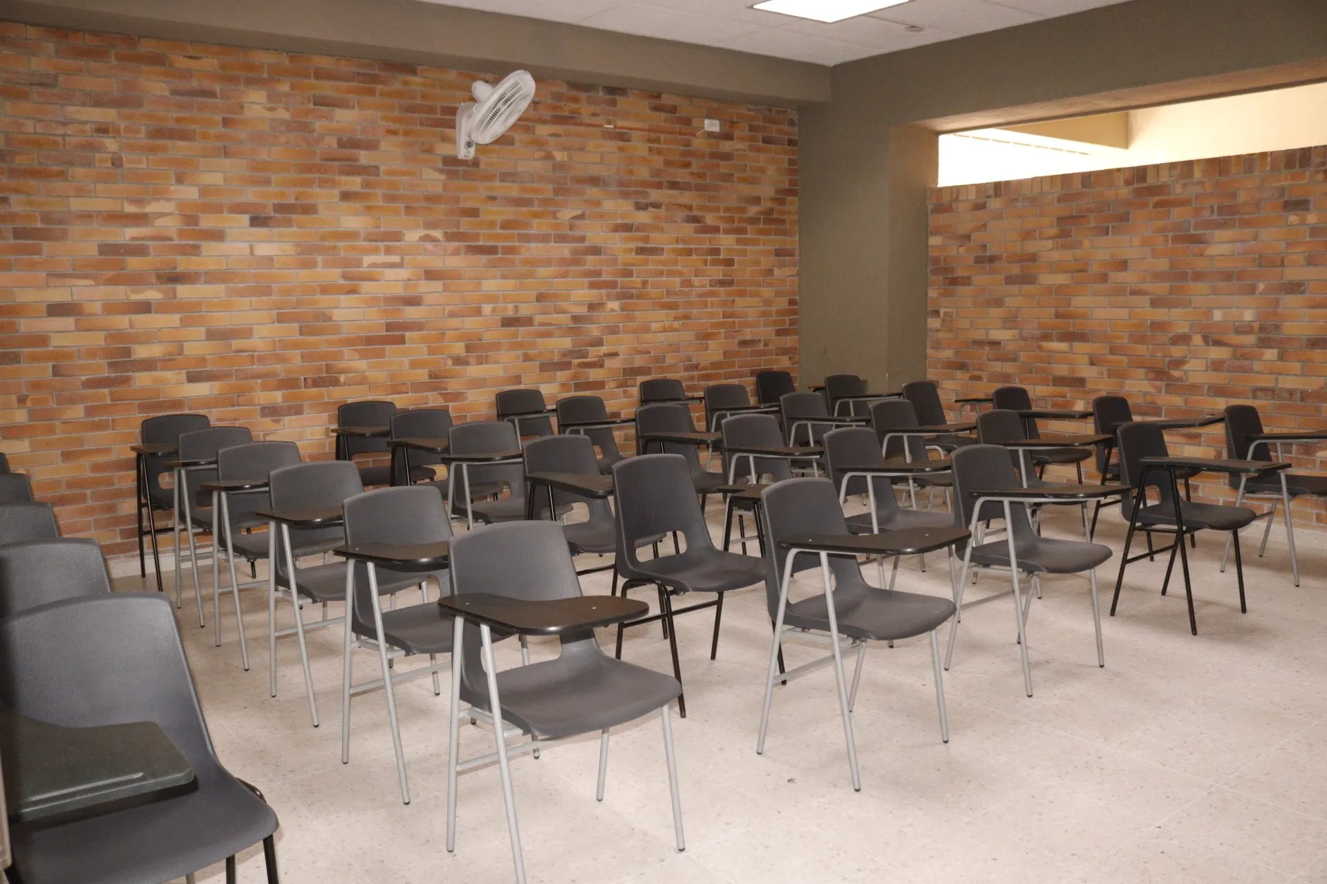 Un aula con filas de sillas y una pared de ladrillos.