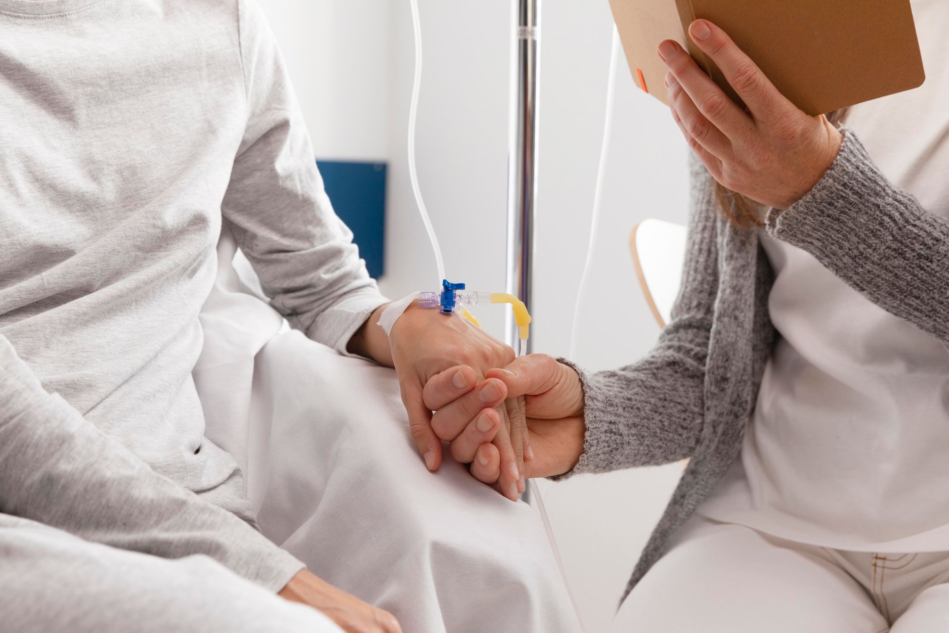 Una mujer sostiene la mano de un paciente en una cama de hospital.