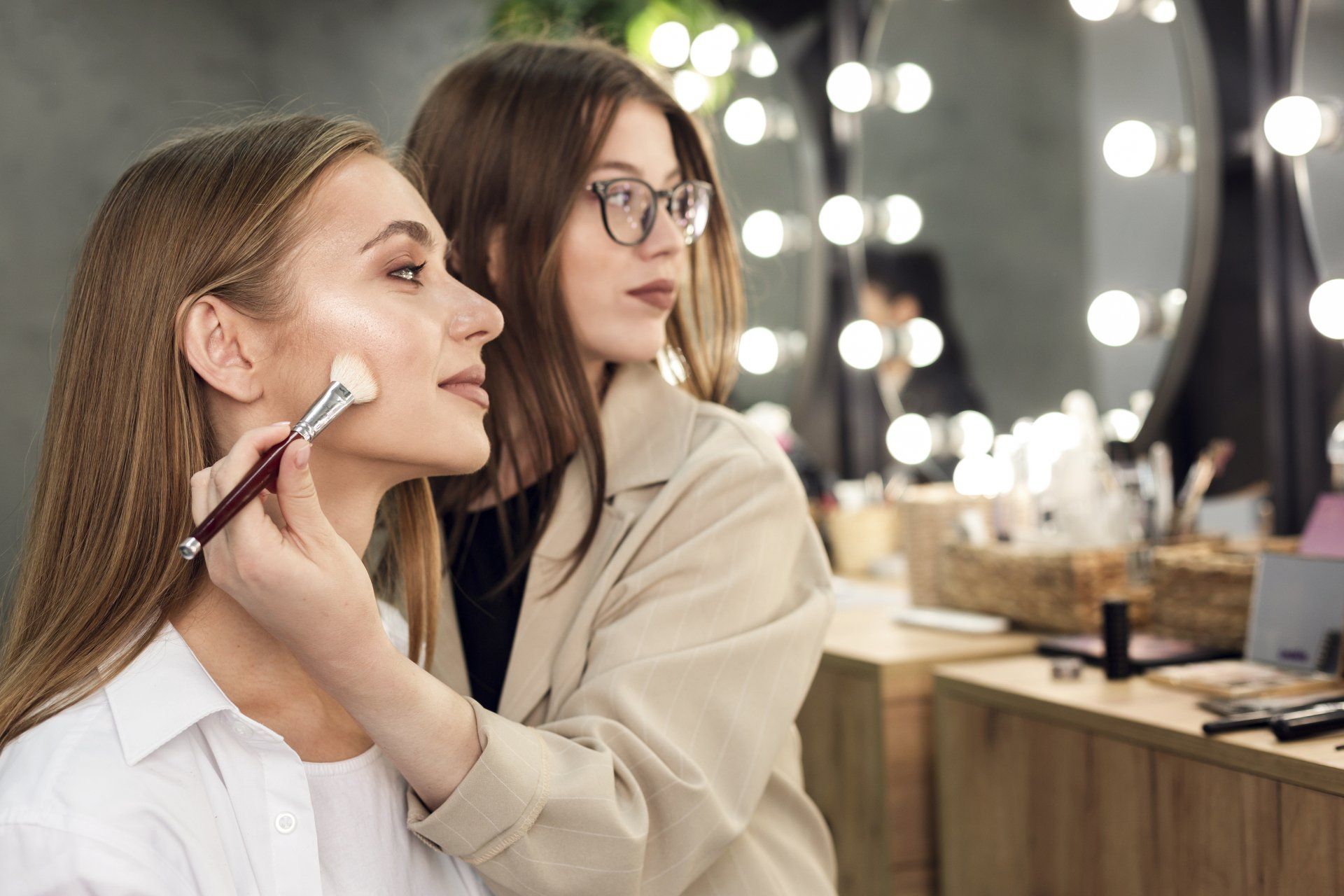 Una mujer está aplicando maquillaje en la cara de otra mujer.