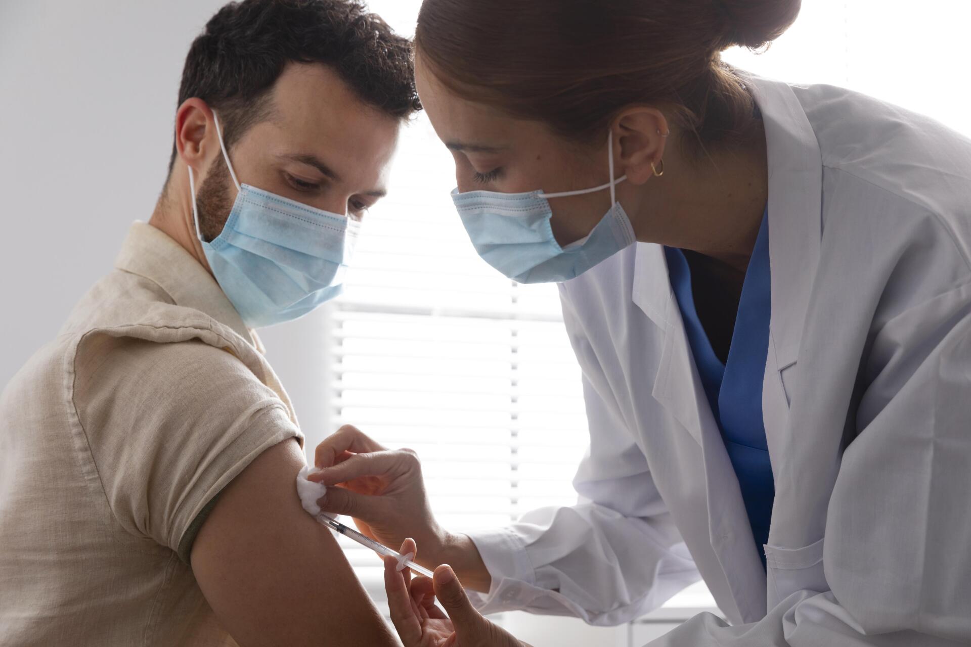 Un médico le está dando a un hombre una inyección en el brazo.