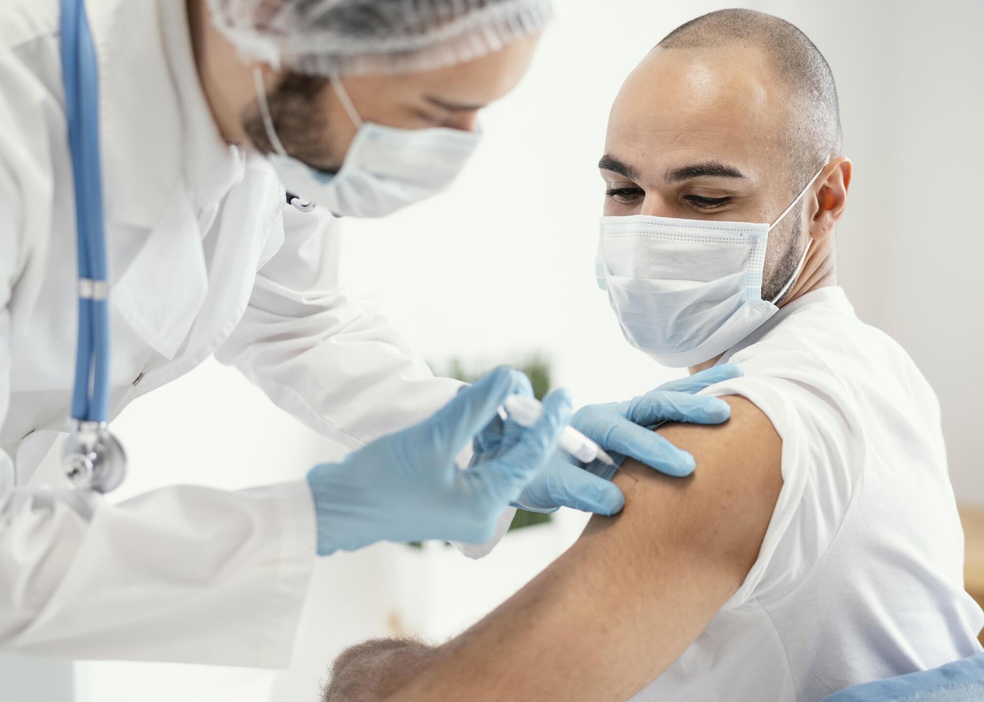 Un médico le está dando a un hombre una vacuna en el brazo.