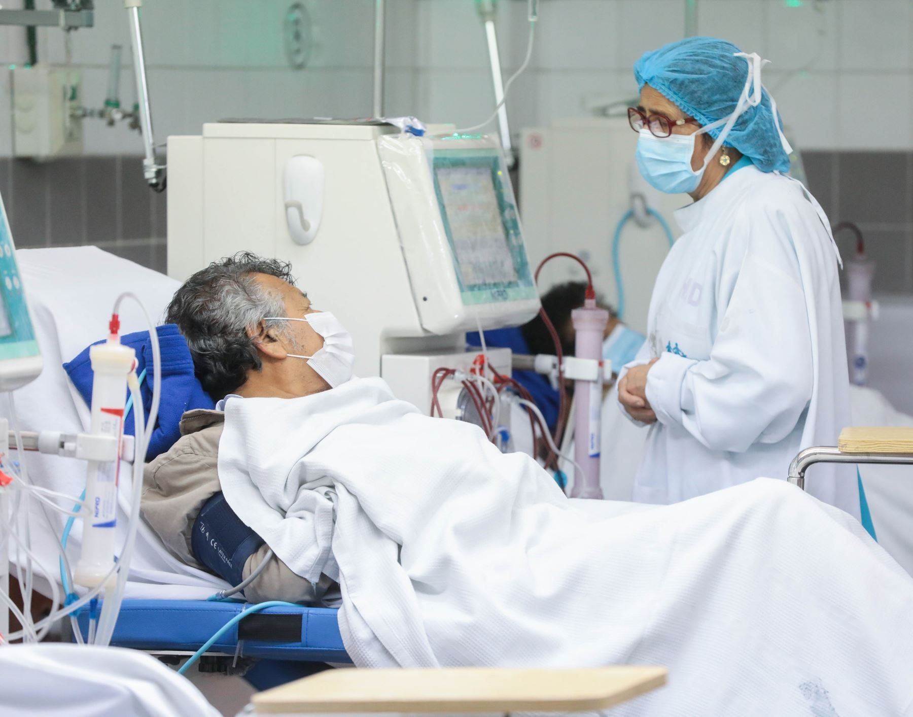 Una enfermera está hablando con un paciente en una cama de hospital.