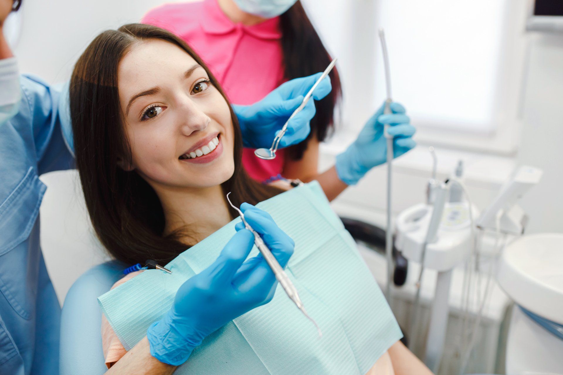 Una mujer está sentada en una silla dental mientras un dentista le examina los dientes.