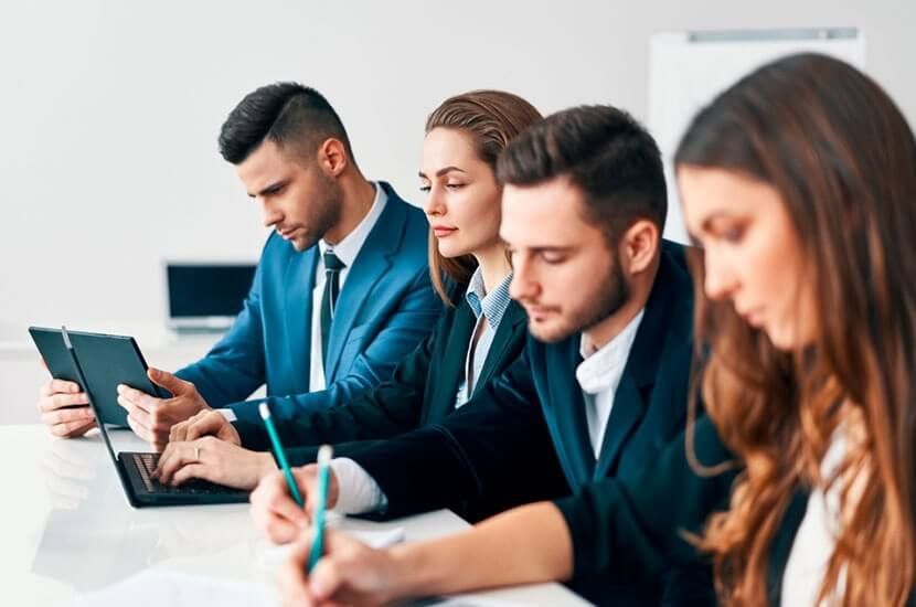 Un grupo de hombres de negocios están sentados en una mesa con computadoras portátiles.