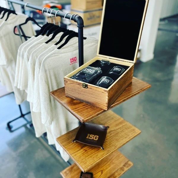 T-shirts on rack and whiskey set in wooden display. Brown tones, merchandise.