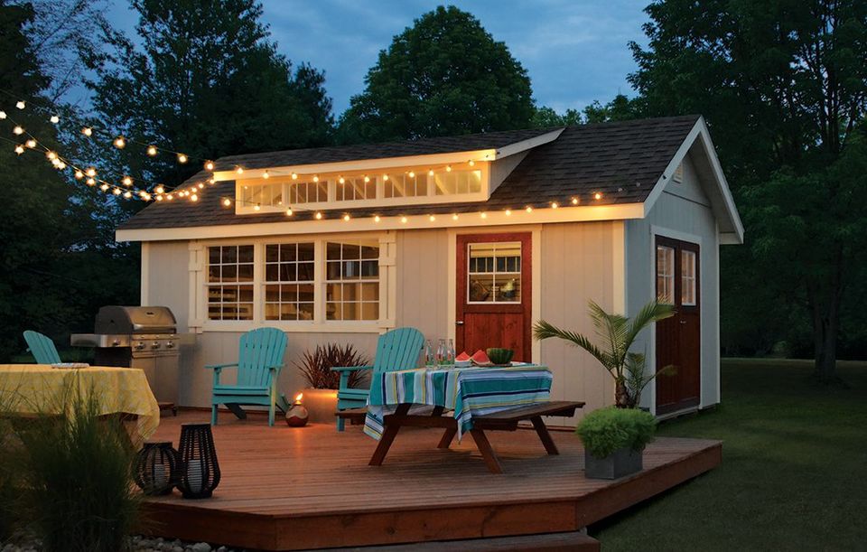 Wooden deck beside a gray house with sliding glass doors, surrounded by trees and bright daylight Wooden deck beside a gray house with sliding glass doors, surrounded by trees and bright daylight