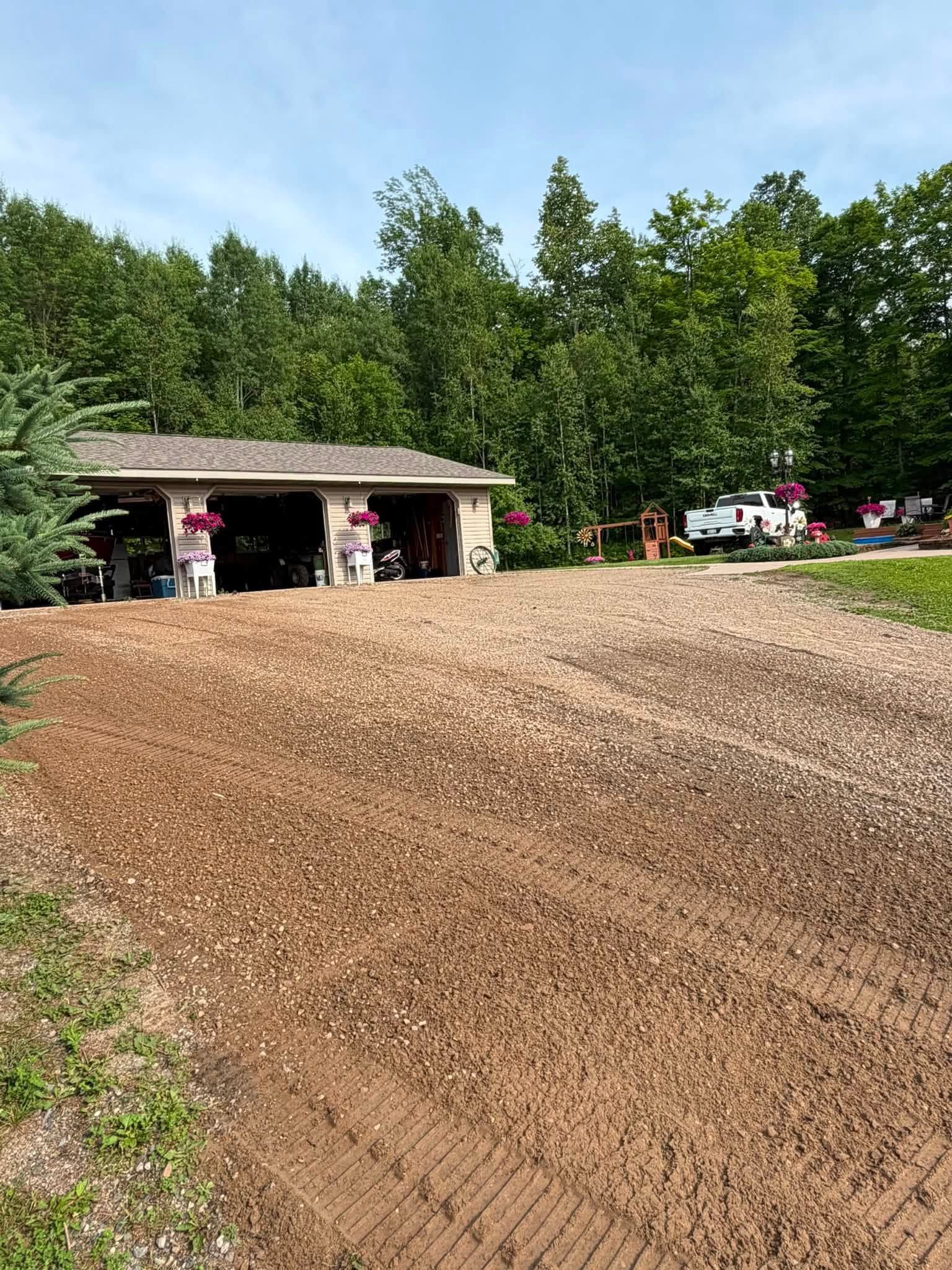 Gravel track at a wooded outdoor venue with people gathered under a small shelter in the background