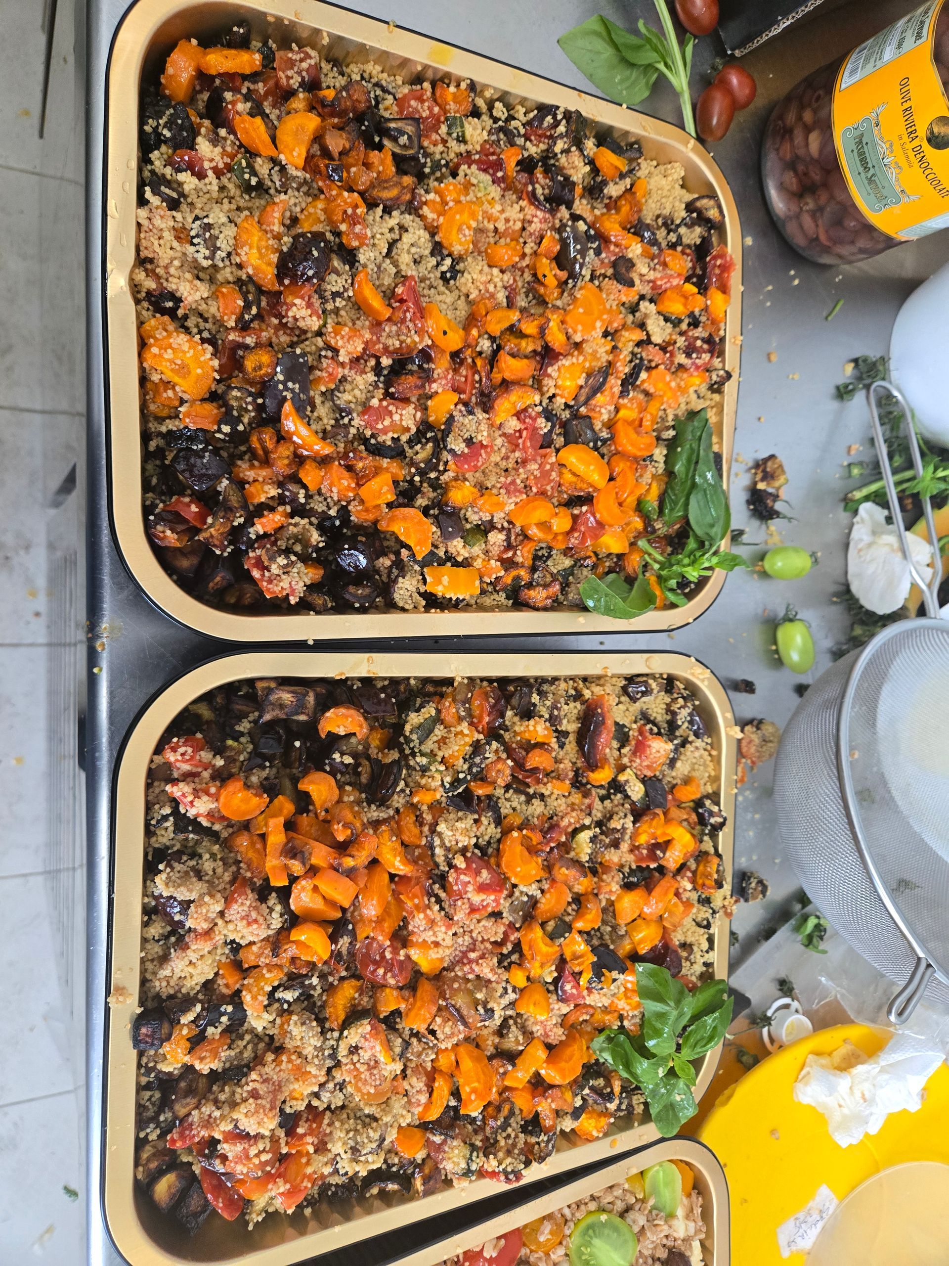 Due vassoi di verdure arrostite con erbe aromatiche su un bancone della cucina.