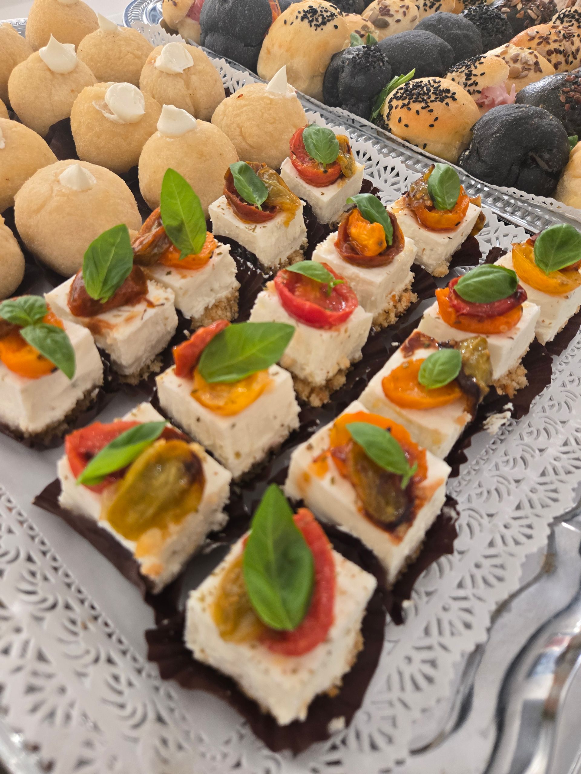 Assortimento di stuzzichini decorati, serviti su un vassoio, con panna, erbe aromatiche e guarnizioni colorate.