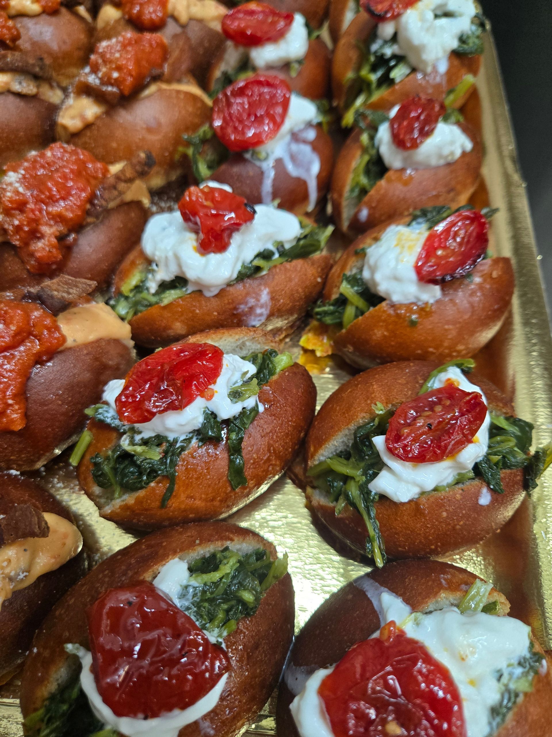Vassoio di pasticcini monoporzione guarniti con panna montata, decorazione verde e ciliegie rosse.