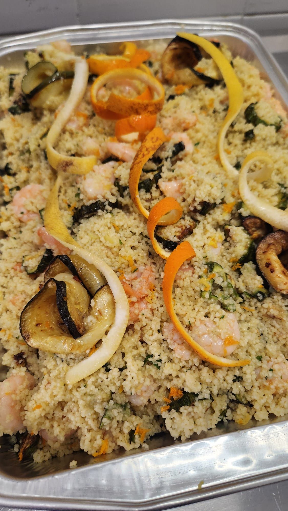 Vassoio di couscous guarnito con peperoni, cipolle e funghi a fette.
