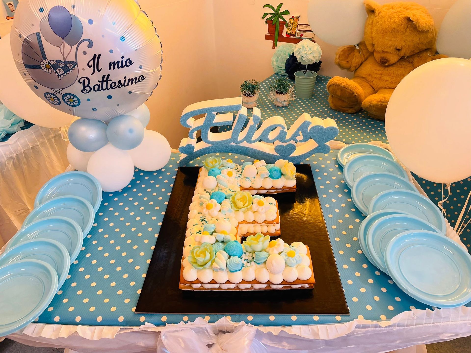 Tavolo per la festa del primo compleanno con orsetto blu, palloncini, torta e decorazioni con il nome