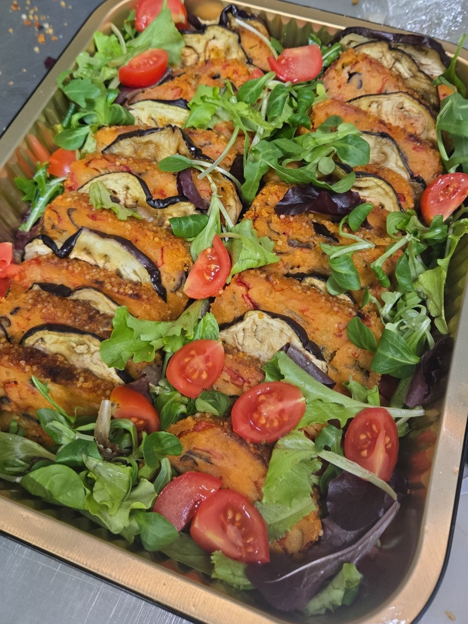 Vassoio di verdure e ortaggi arrostiti con pomodorini, disposti su una teglia da forno.