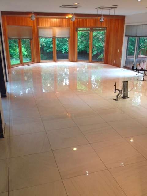 Large room with shiny tiled floor, wooden walls, large windows looking out onto trees.