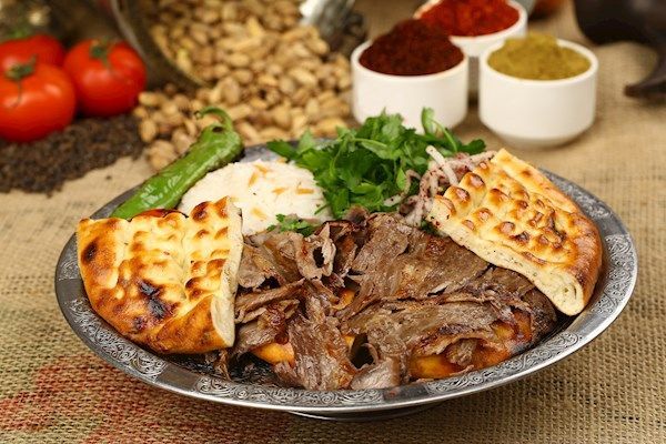 A plate of food with meat , bread and vegetables on a table.