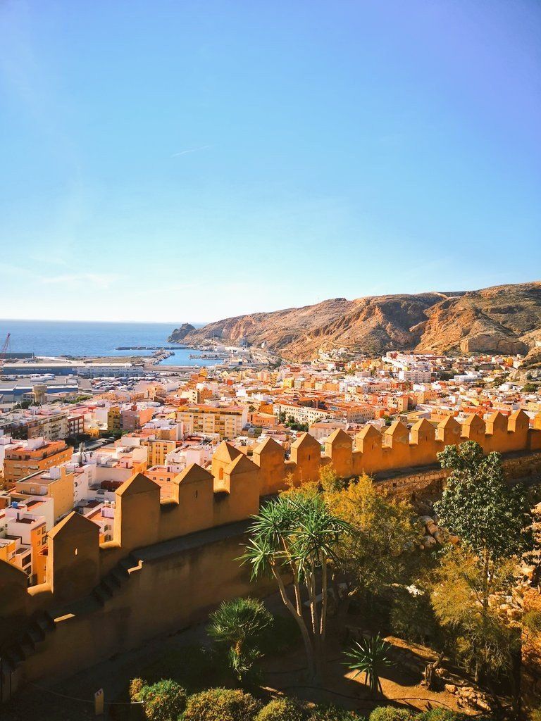 An aerial view of a city with a wall in the foreground and the ocean in the background.