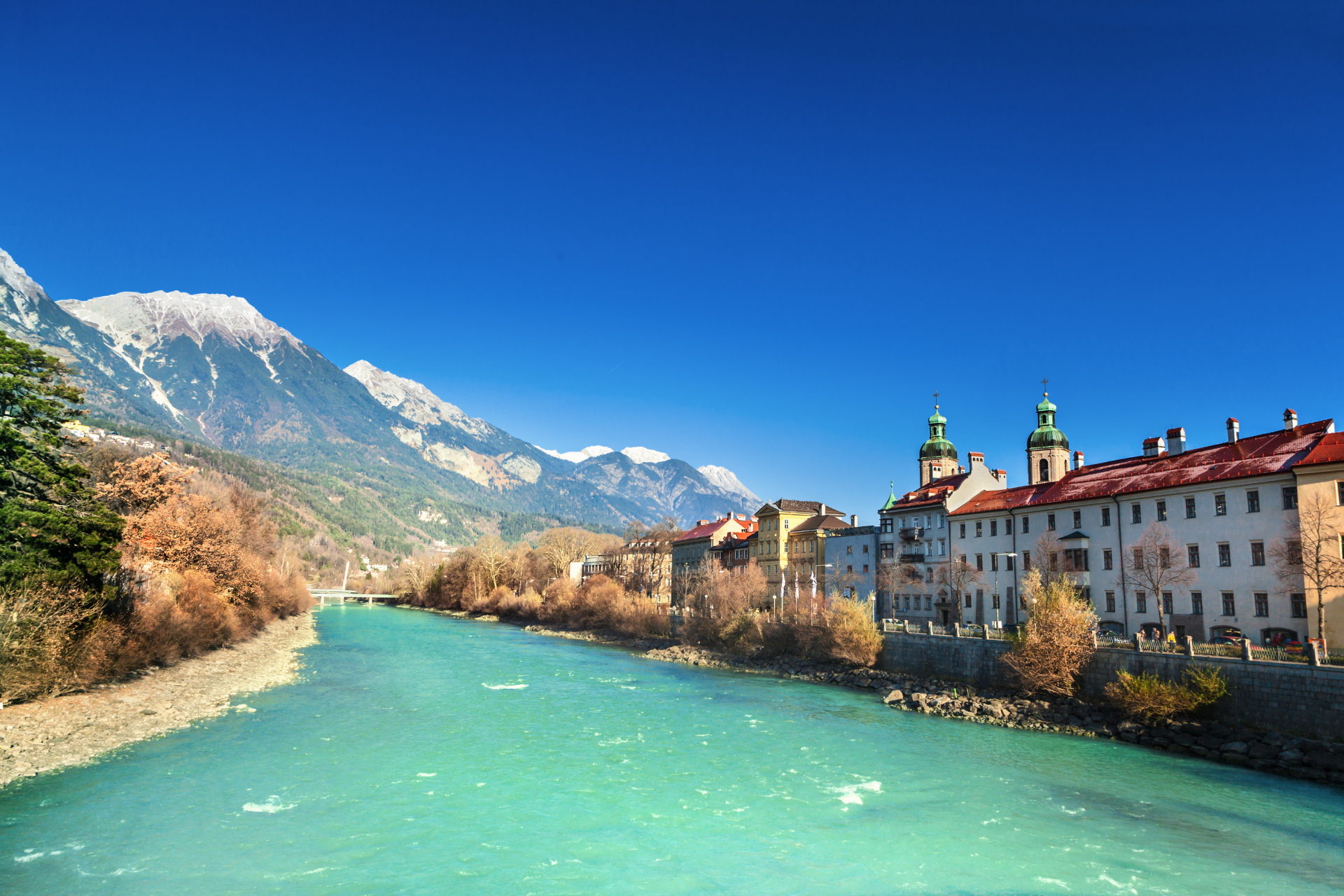 A river runs through a city with mountains in the background.