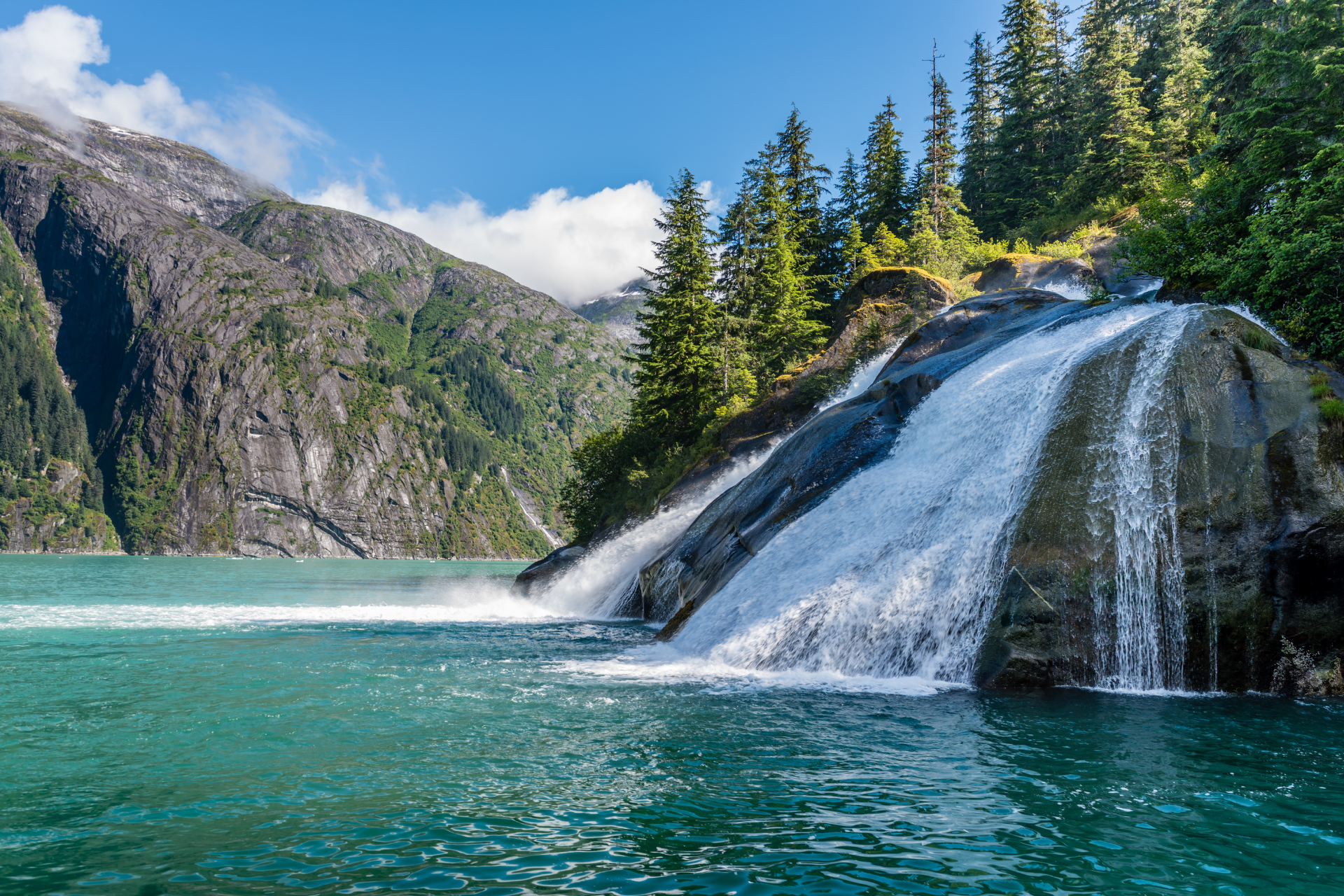 There is a waterfall in the middle of a lake surrounded by mountains.