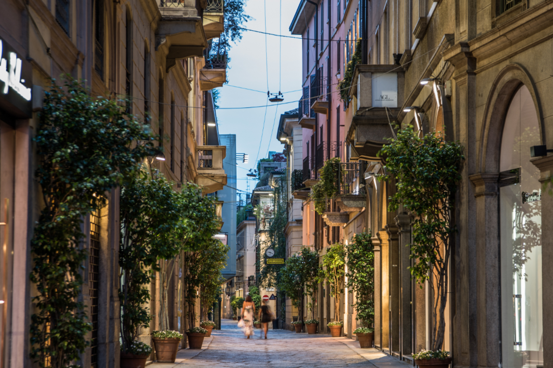 A couple of people are walking down a narrow street between two buildings.