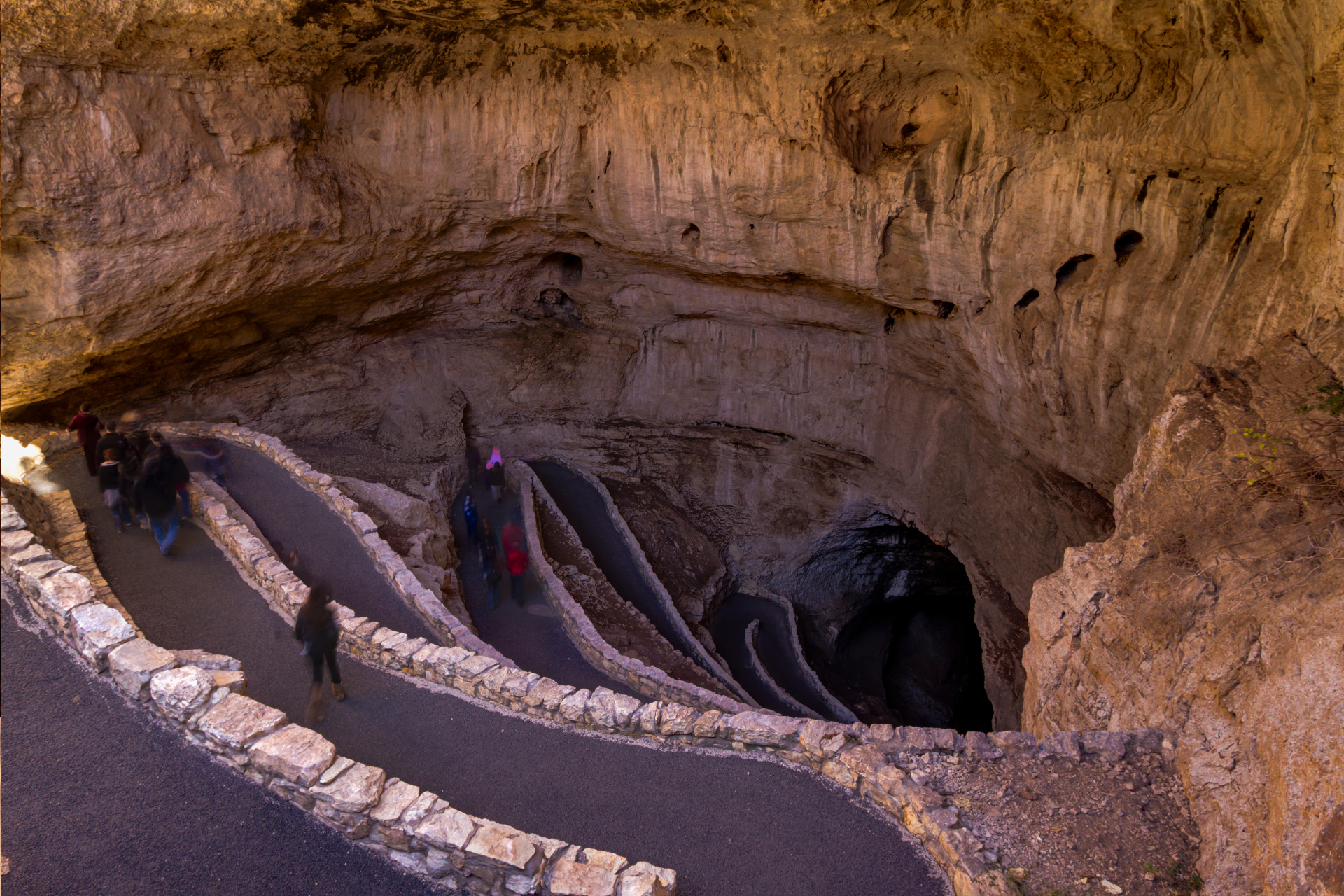 A group of people are walking down stairs in a cave.