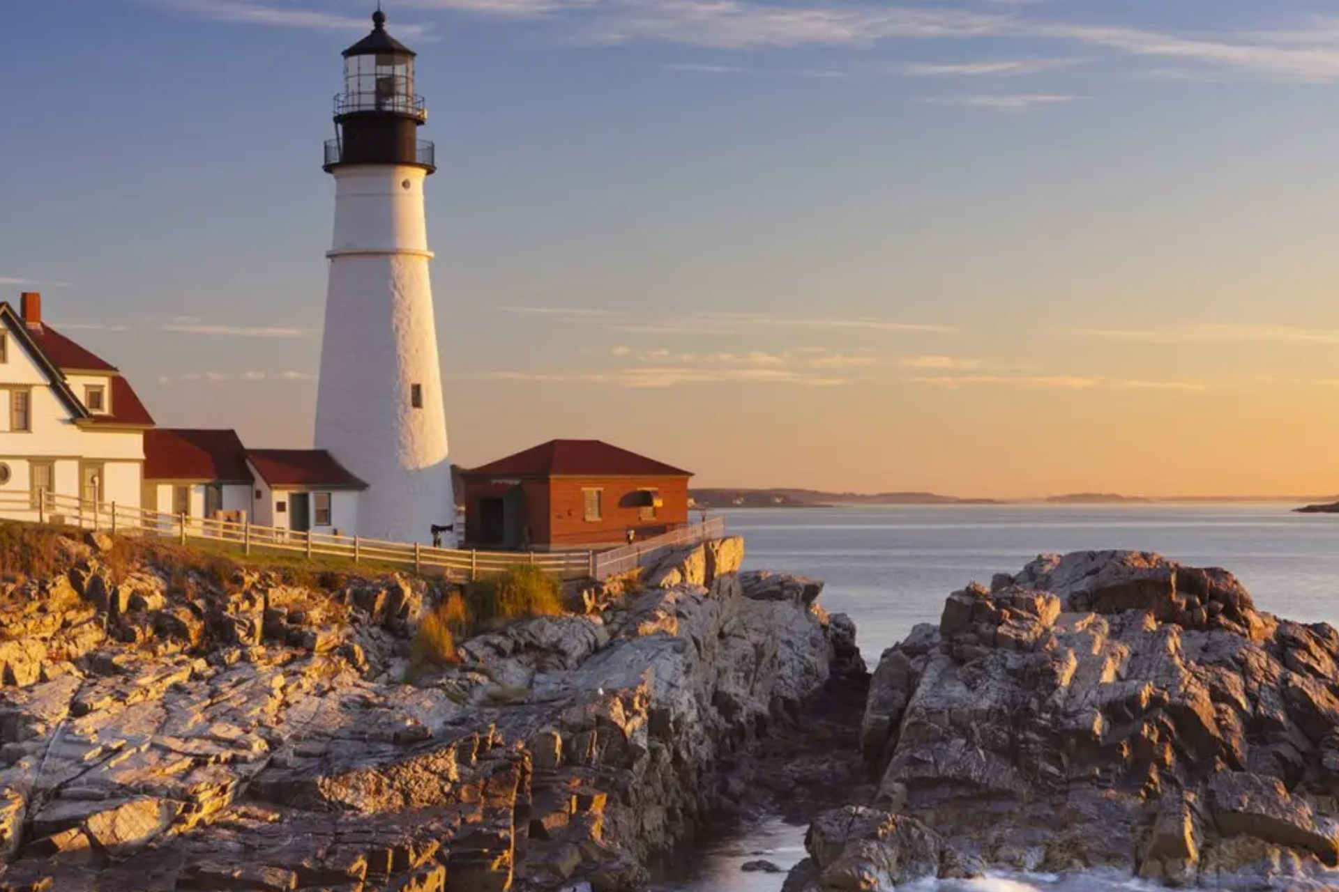 A lighthouse is sitting on top of a rocky cliff overlooking the ocean.