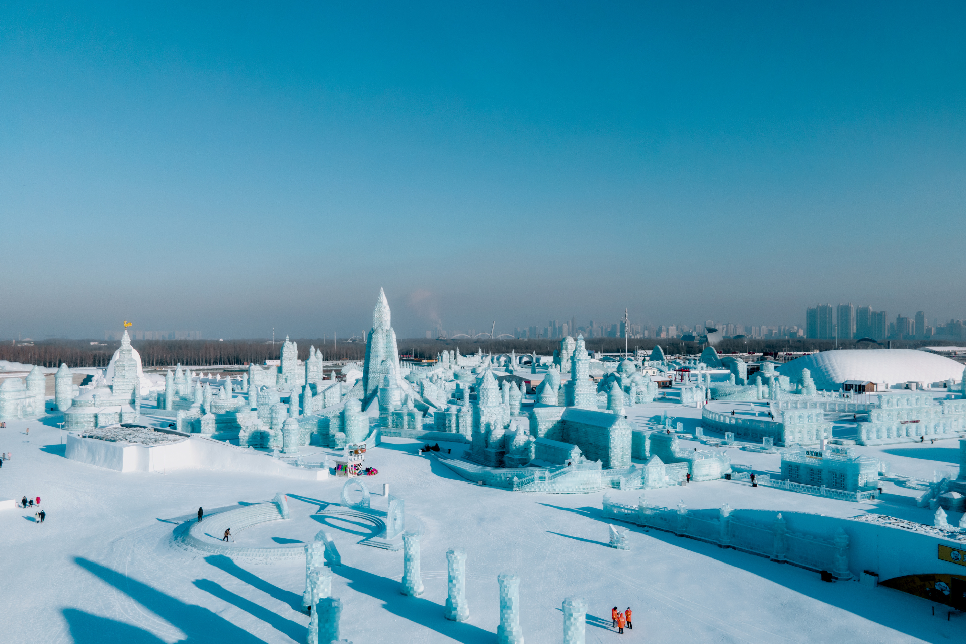 An aerial view of a snow sculpture park with a city in the background.