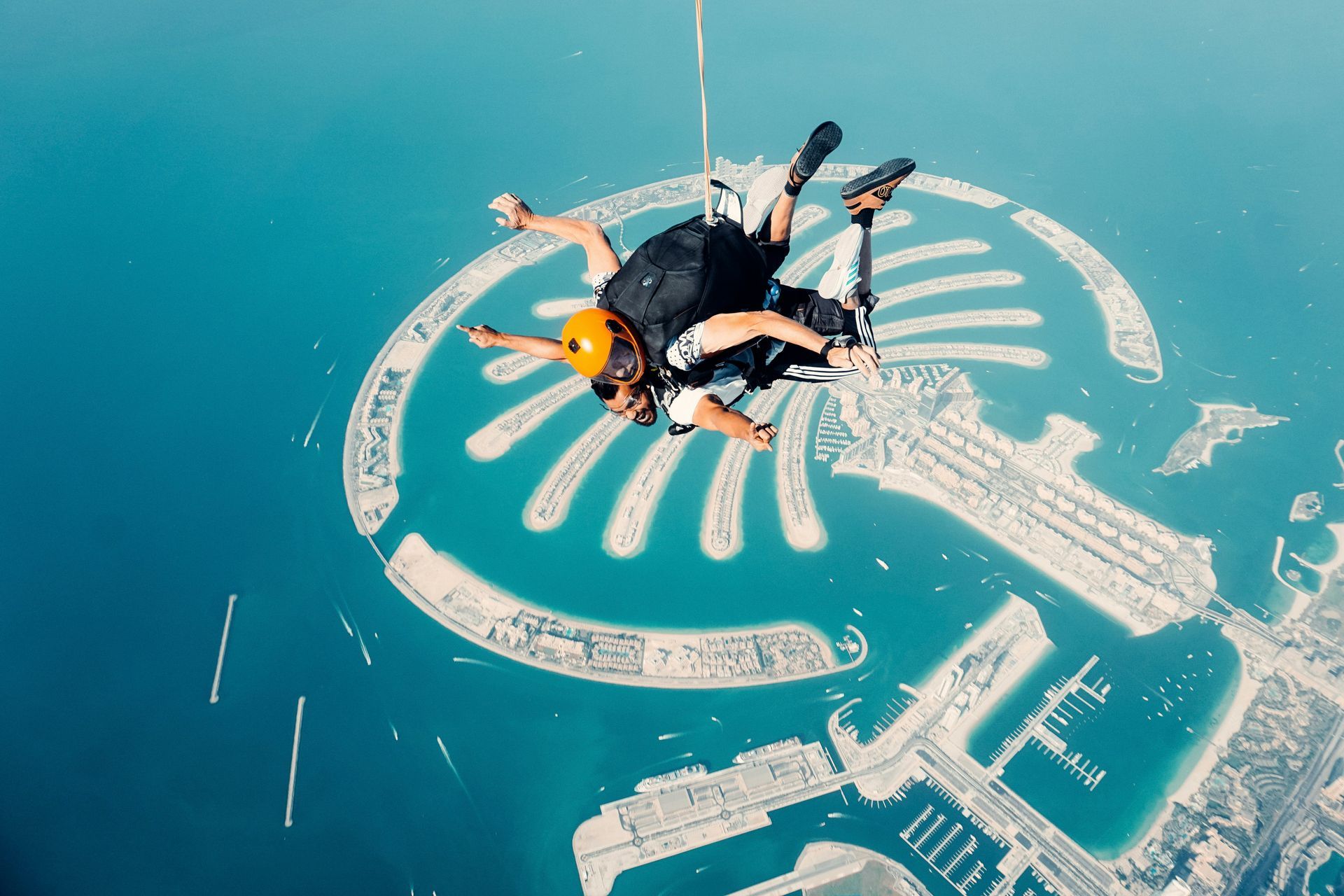 A person is flying through the air over a small island in the middle of the ocean.