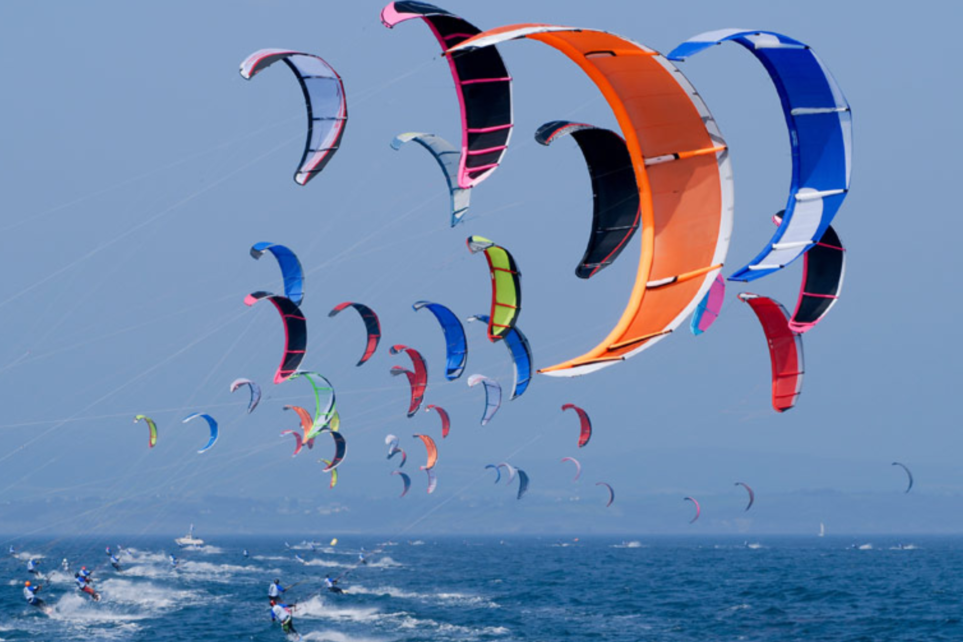 A bunch of kites are flying over the ocean