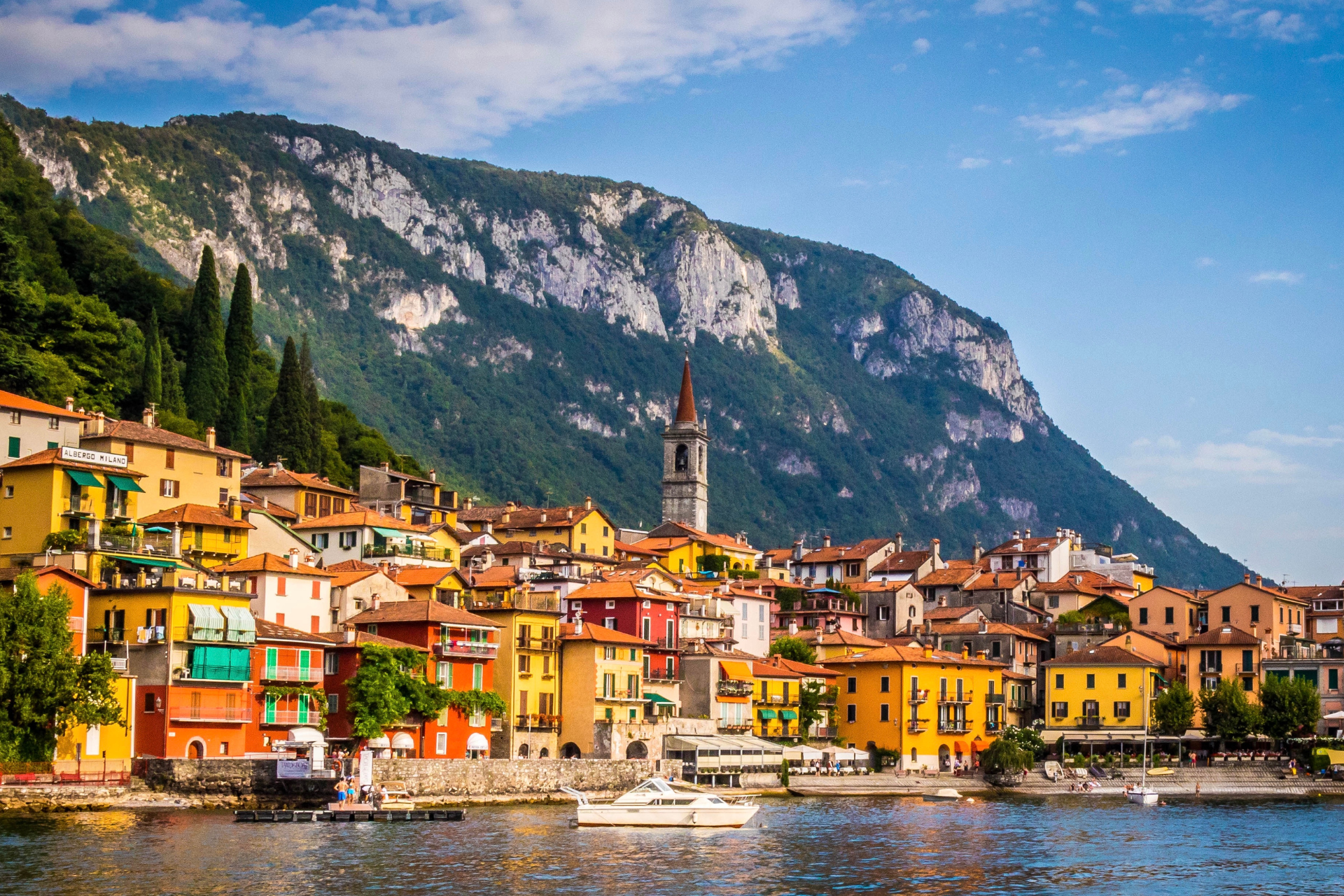 A small town on the shore of a lake with mountains in the background.