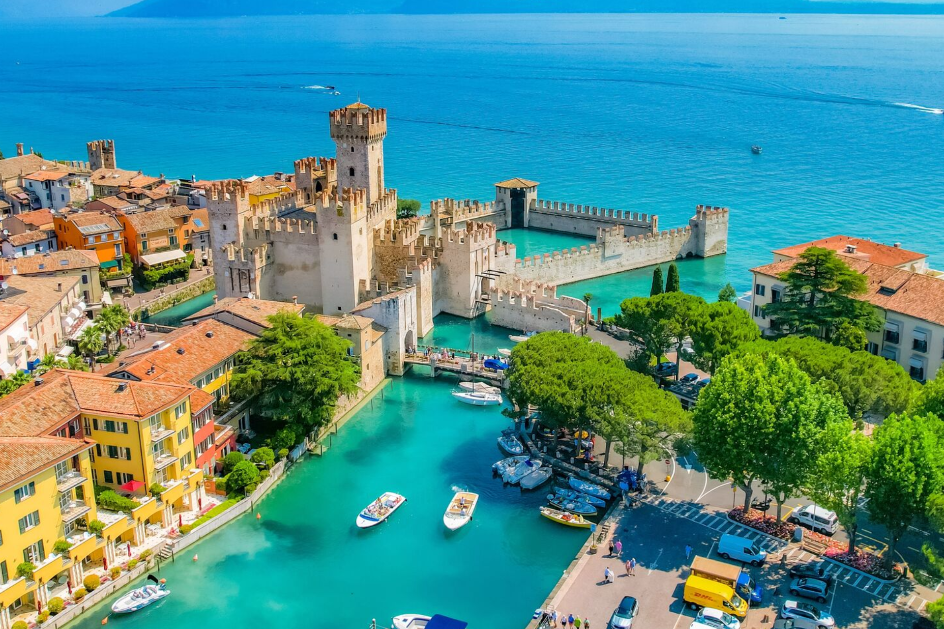 An aerial view of a castle in the middle of a lake with boats in the water.