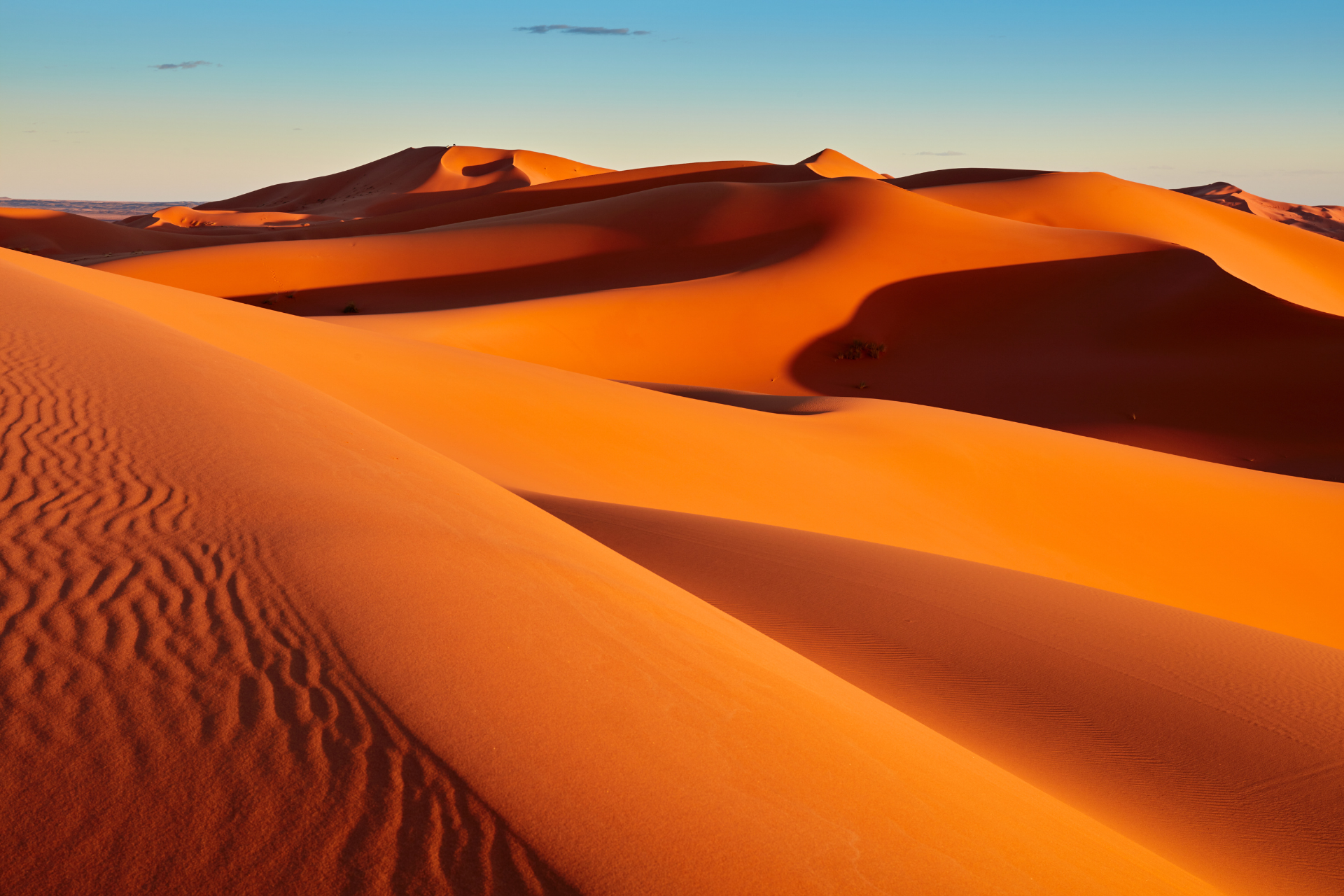 Sand dunes in the desert with a blue sky in the background