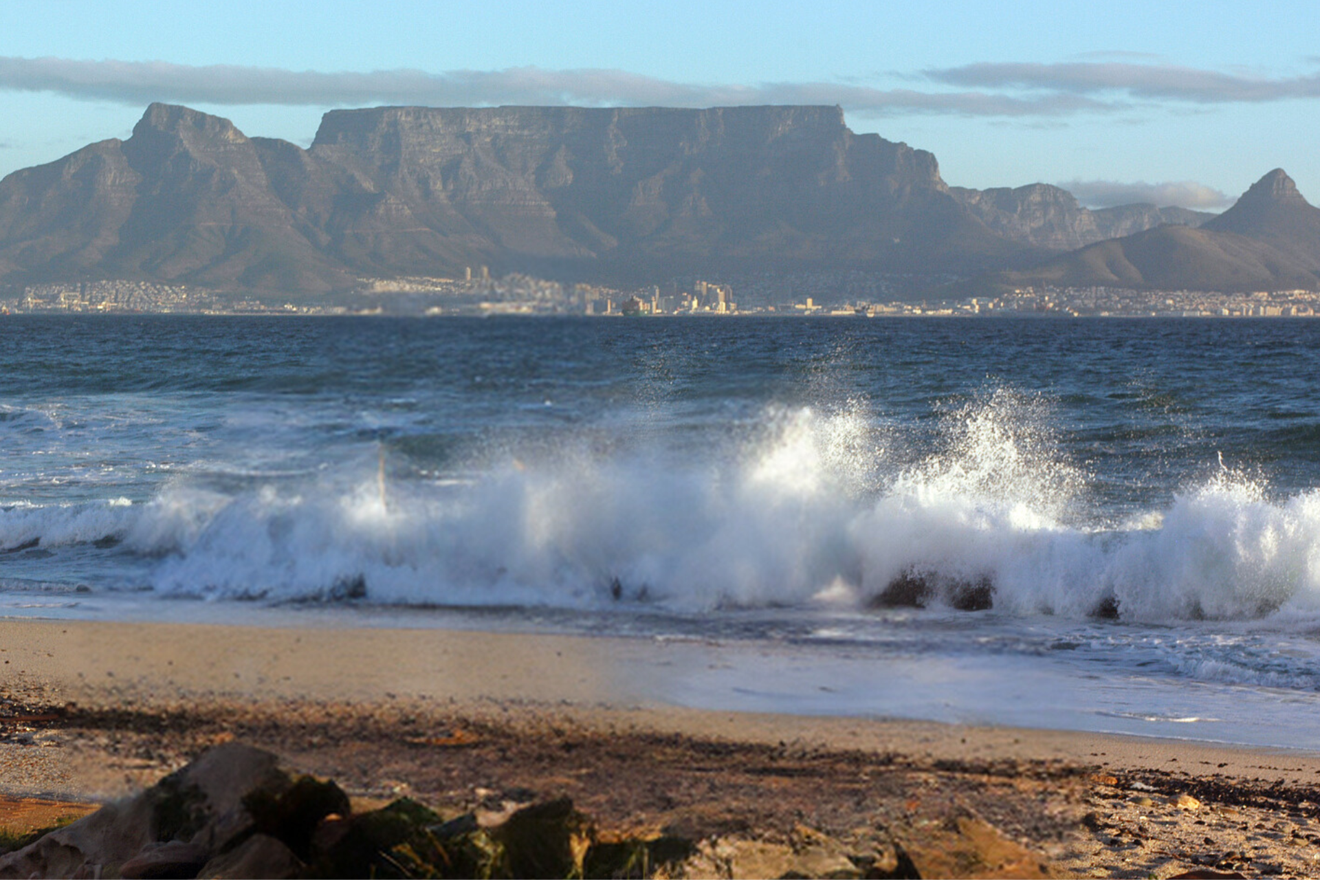 Waves crashing on a beach with a mountain in the background